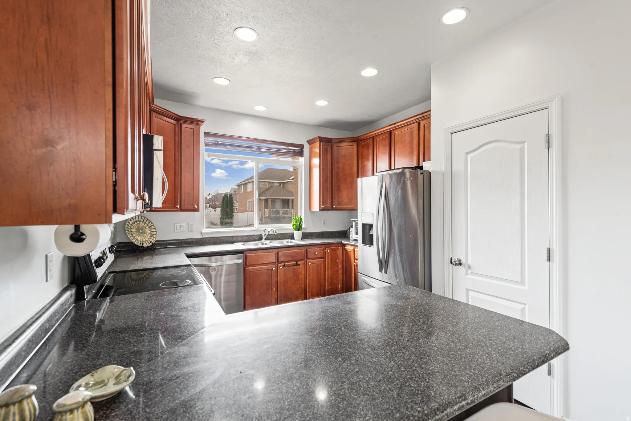 Kitchen with dark countertops, a peninsula, stainless steel appliances, a textured ceiling, and recessed lighting