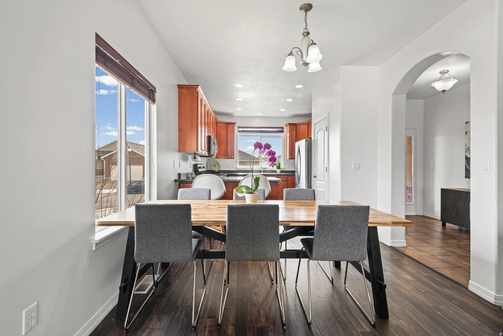 Dining room featuring arched walkways, dark wood-style flooring, and suspended lighting