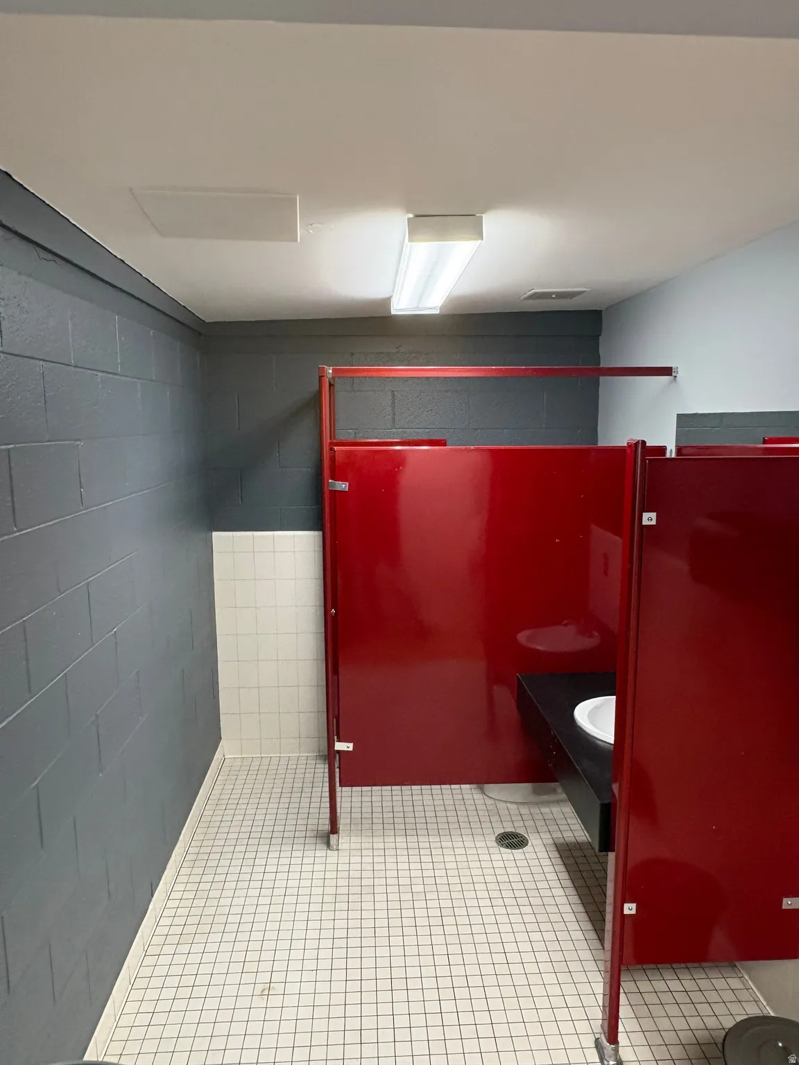 Bathroom with light tile patterned floors and concrete block wall
