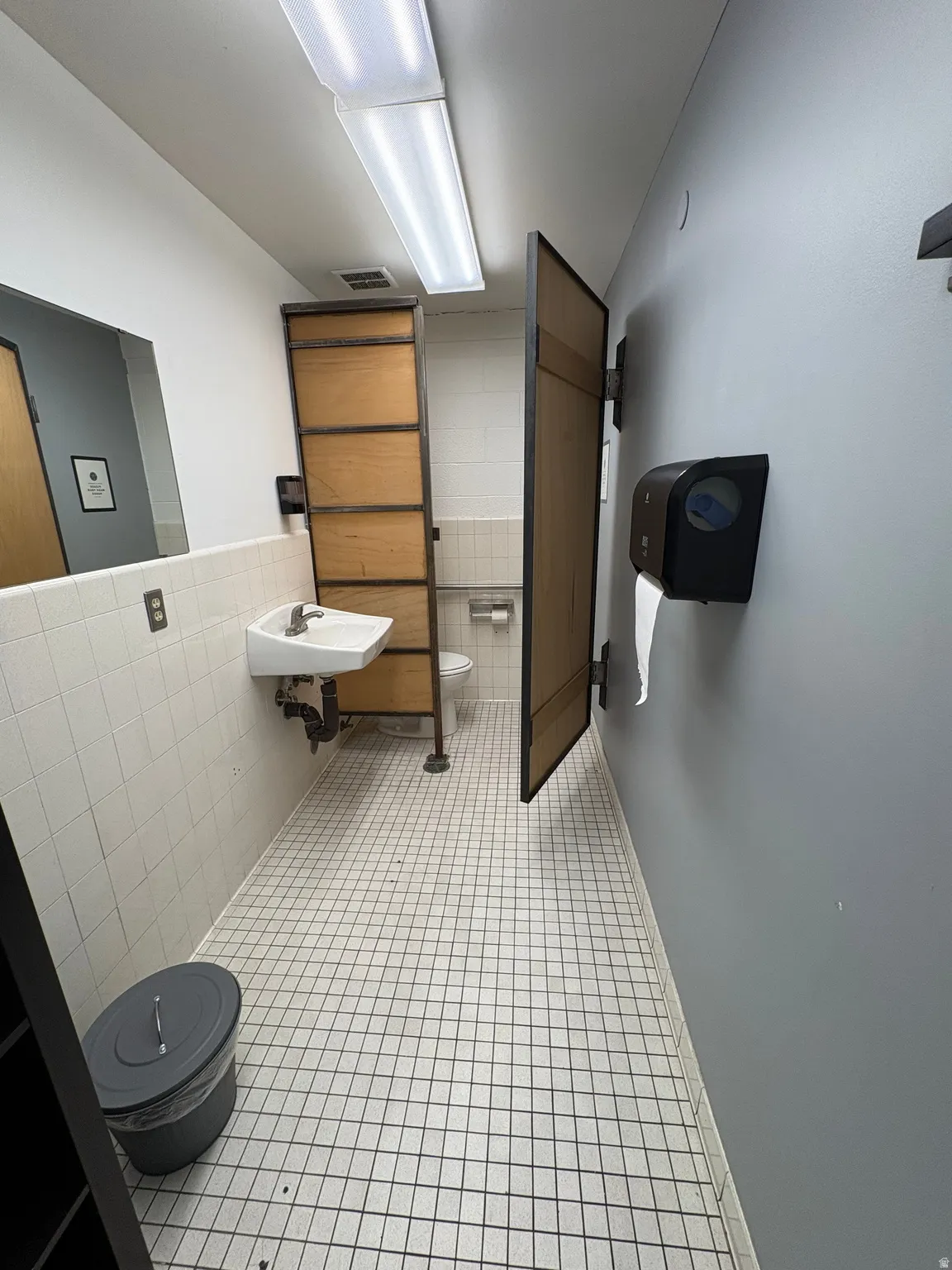 Bathroom featuring toilet and tile walls