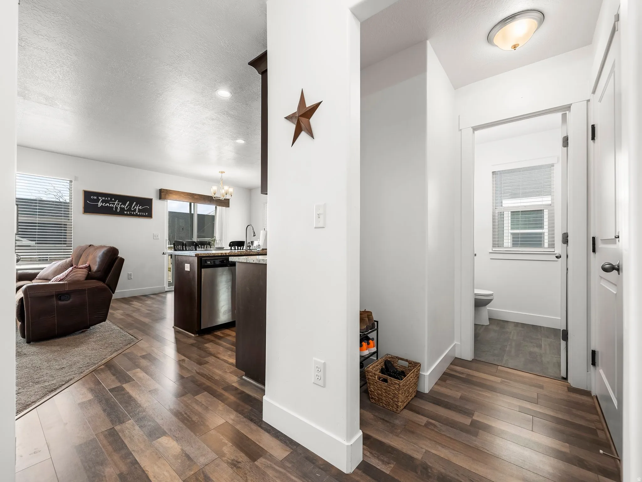Hall with dark wood-style flooring, healthy amount of natural light, hanging lights, and a textured ceiling