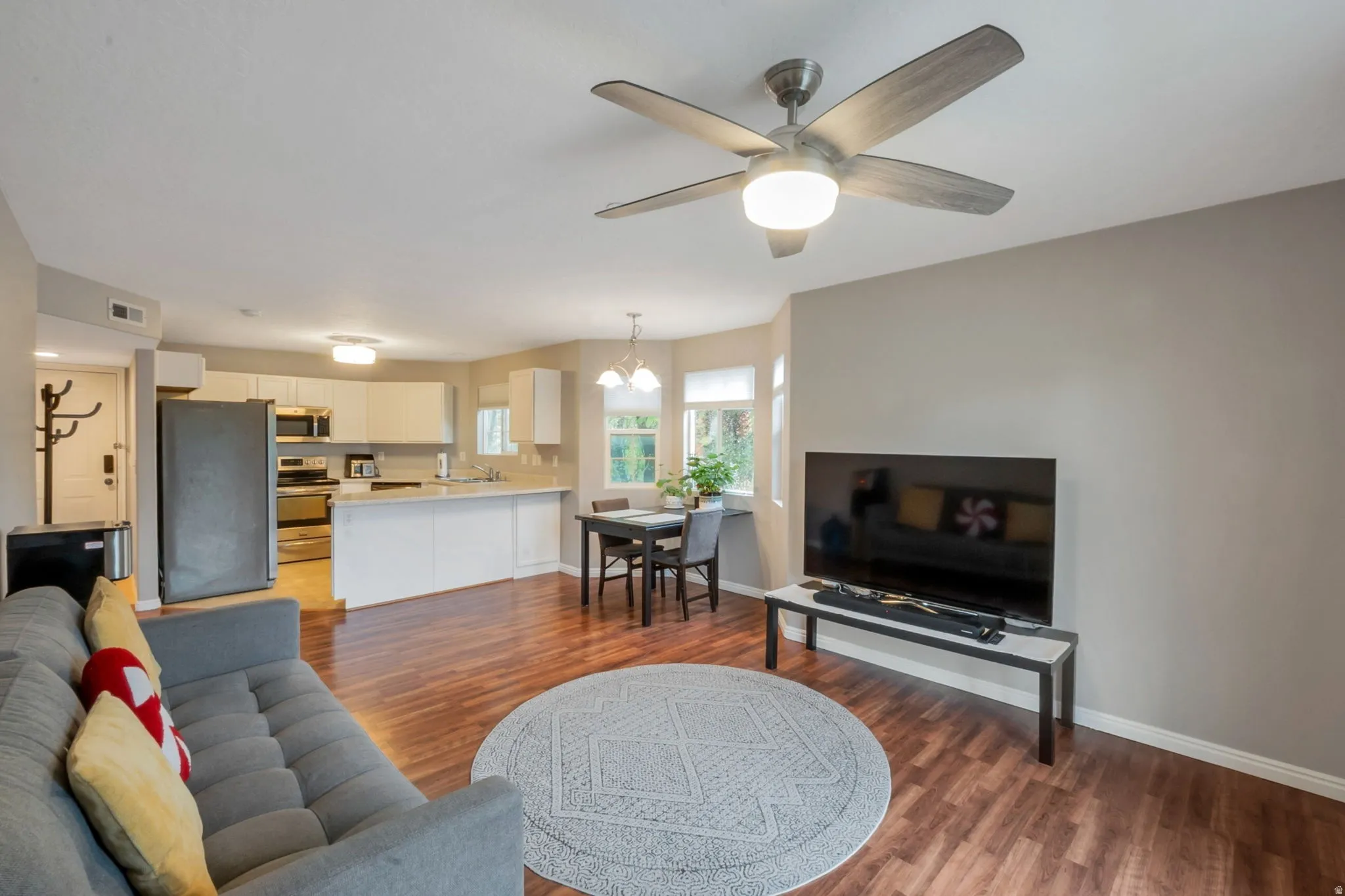 Open-concept living area with wood-finish flooring, a contemporary ceiling fan, and neutral paint tones