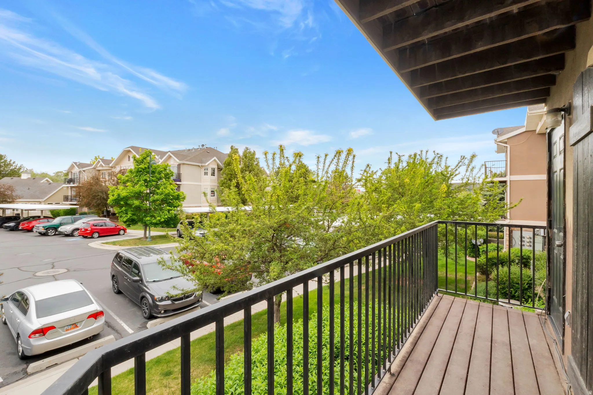 Private balcony featuring wood-finish decking and black metal railings