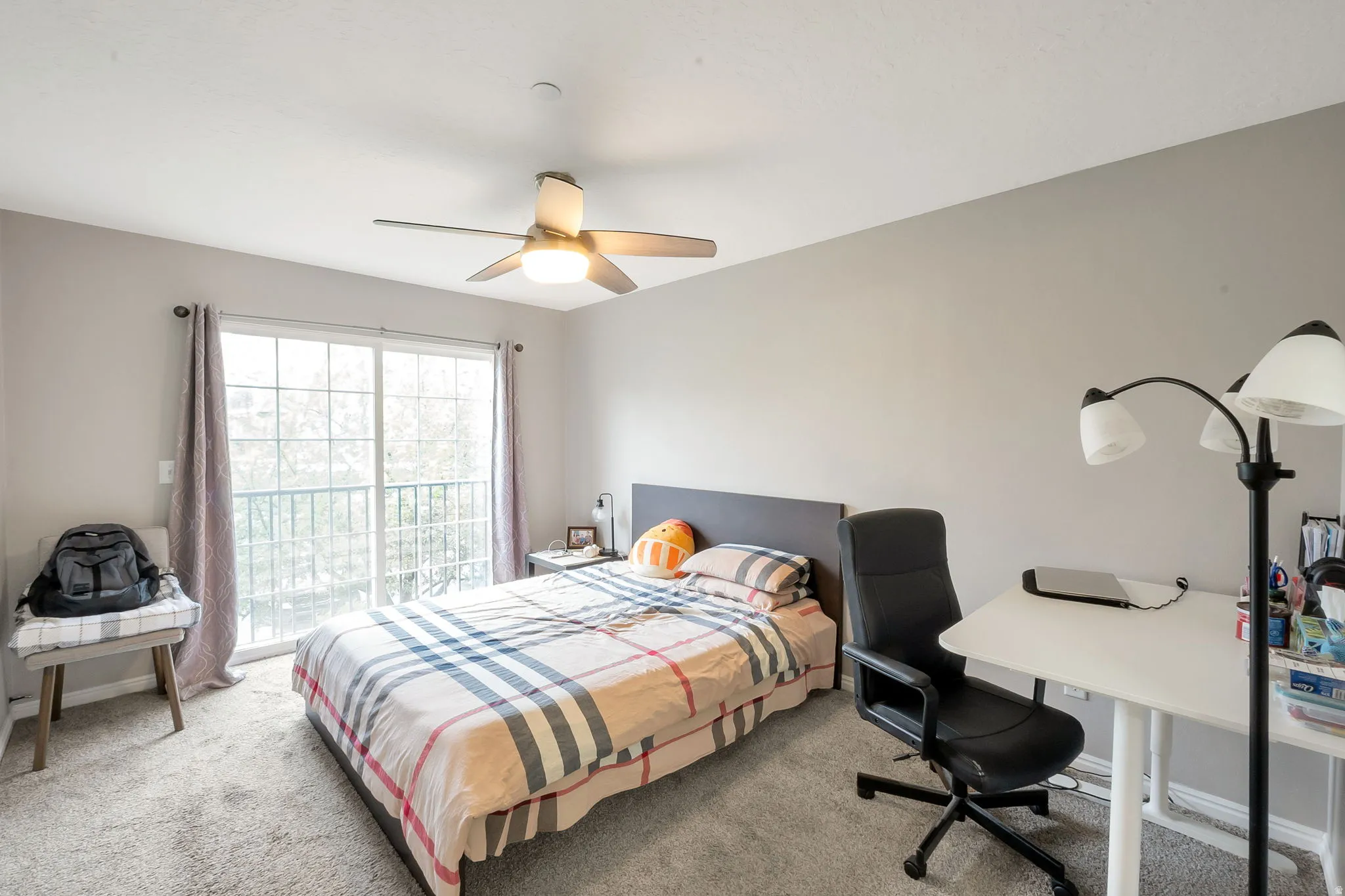 Bedroom featuring neutral wall colors, light-toned carpeting, a ceiling fan with integrated lighting, and a sliding glass door providing exterior access