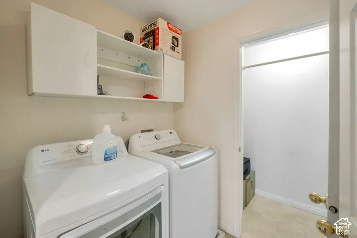 Laundry area featuring white wall cabinetry with open shelving, light-toned wall paint, and tiled flooring