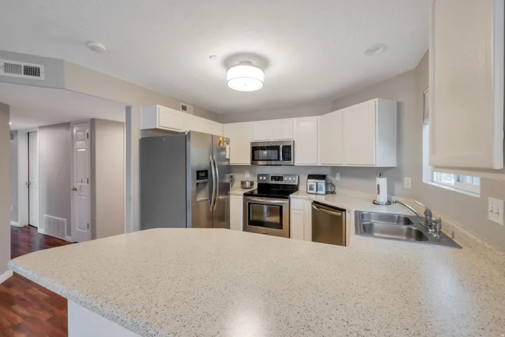 Kitchen featuring white cabinetry, stainless steel appliances, a double basin sink, and ample countertop space