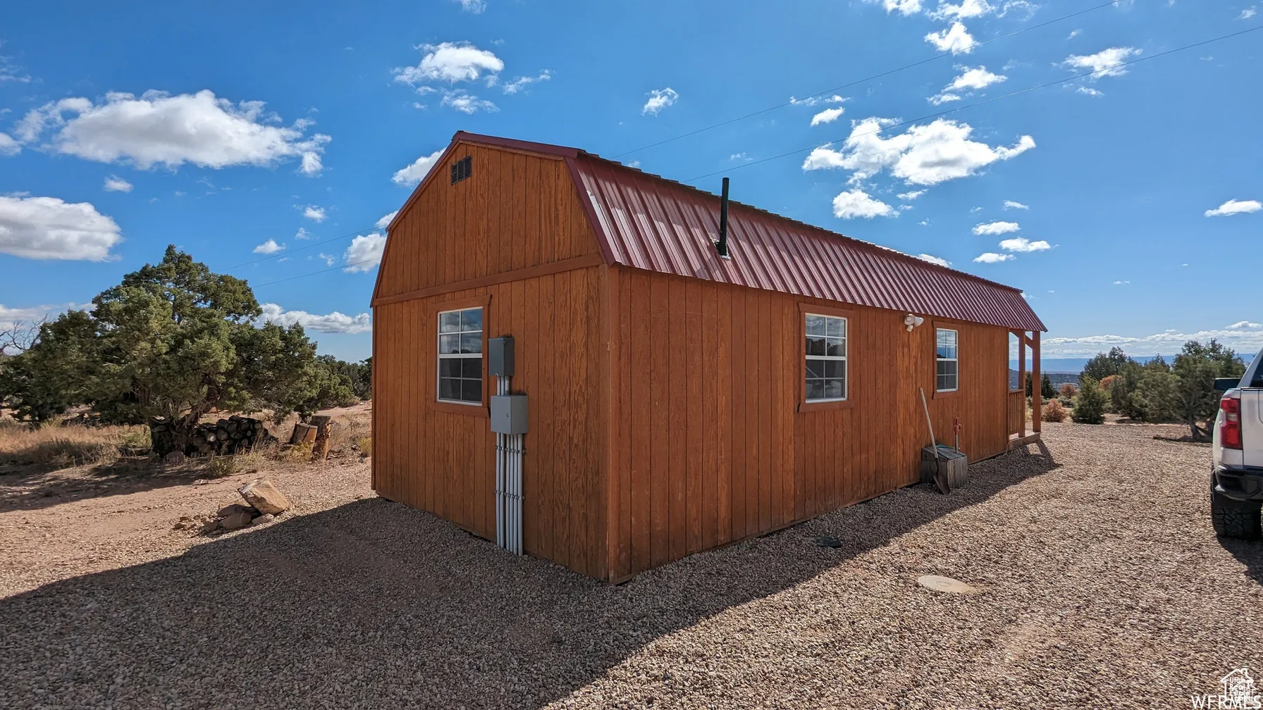 View of property exterior with a gambrel roof, a metal roof, and an outbuilding