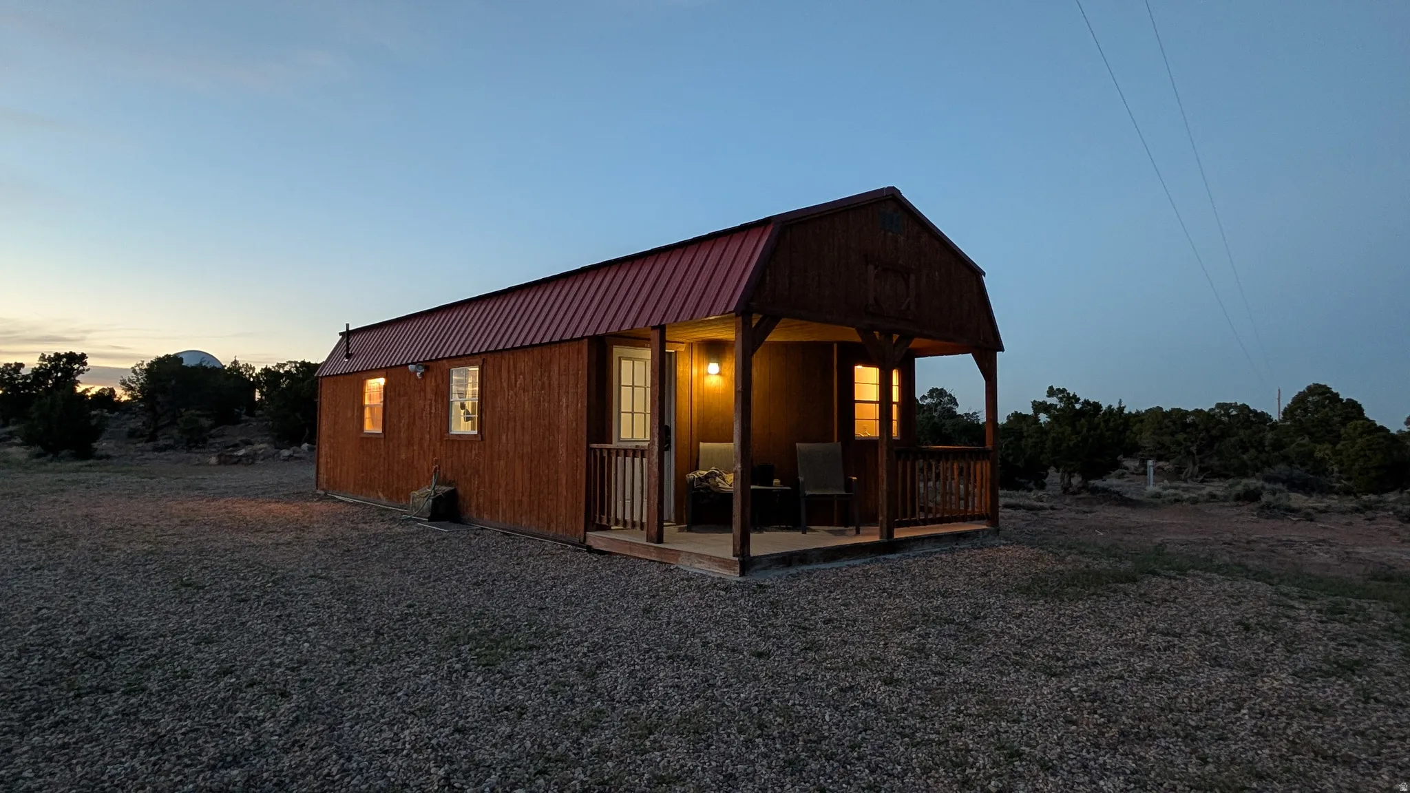 Wood-sided barn-style structure featuring a red metal roof and a covered front porch