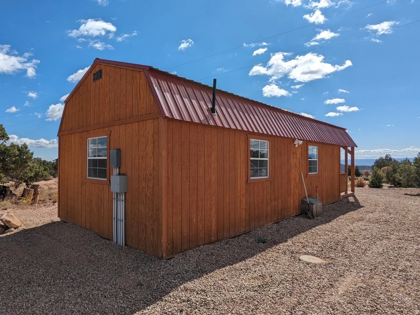 View of property exterior with a gambrel roof, a metal roof, and an outbuilding