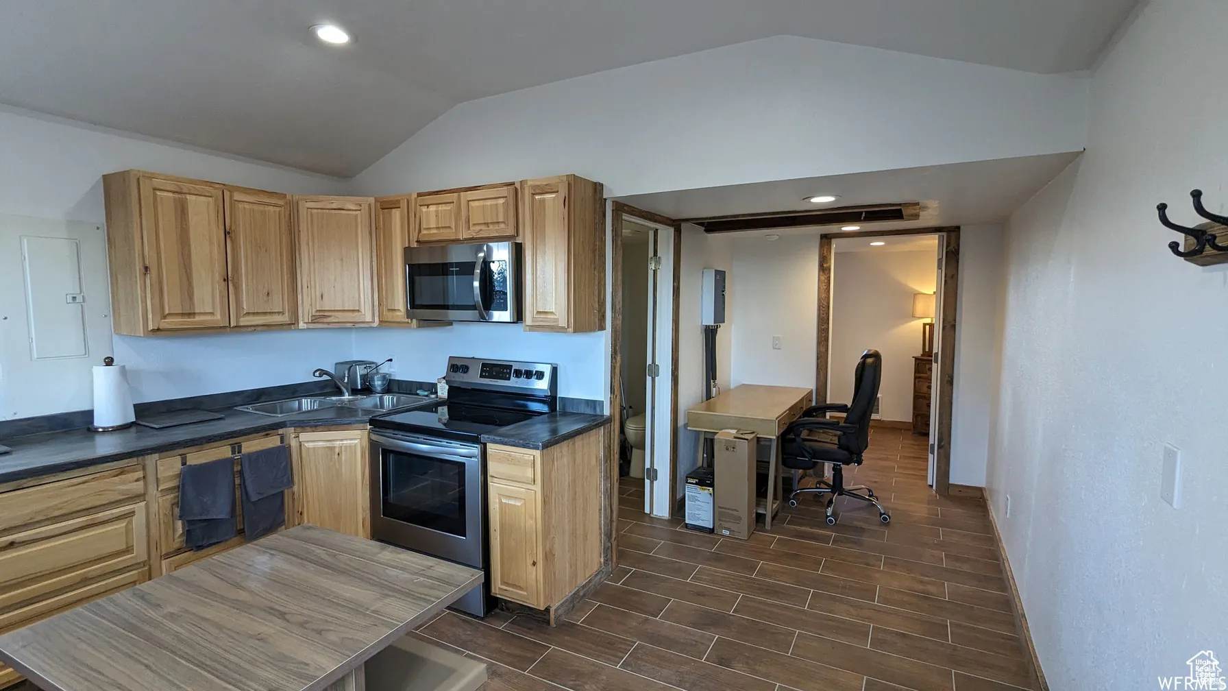 Kitchen with stainless steel appliances, wood tiled floors, an office area, and dark countertops