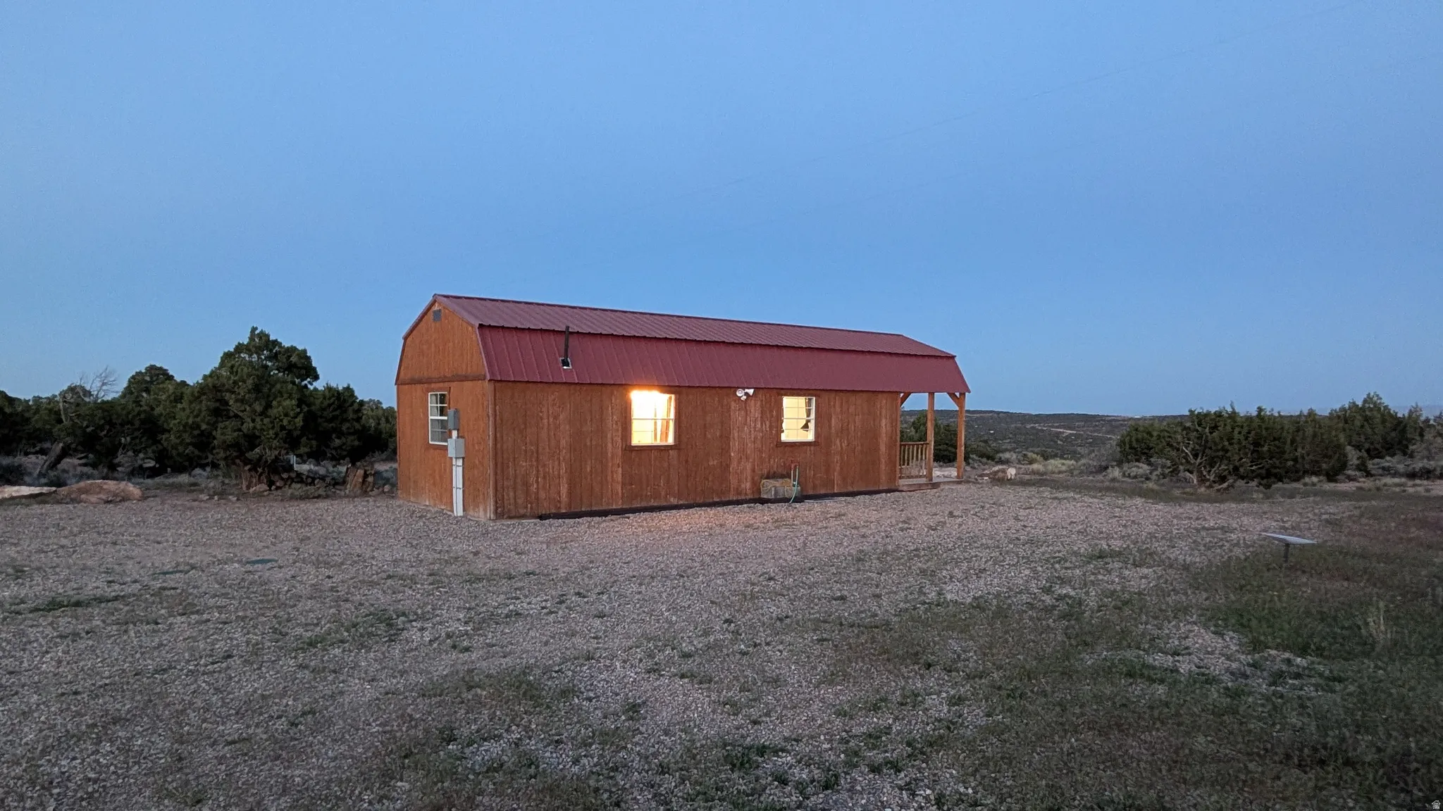 Barn-style structure featuring a red metal gambrel roof and wood-finish siding