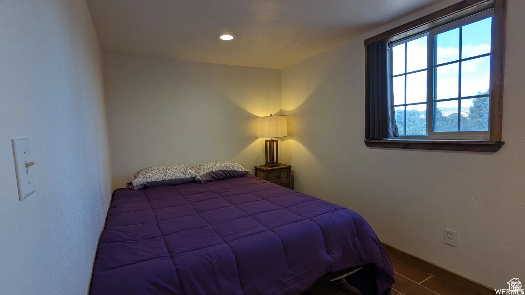 Bedroom featuring dark wood-type flooring and a textured wall