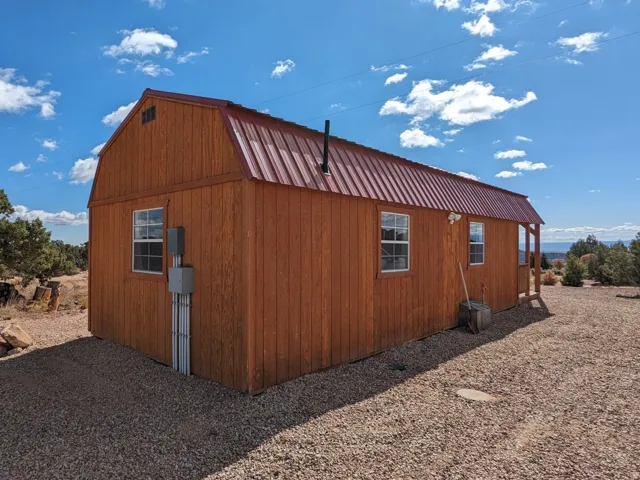 View of property exterior with a gambrel roof, a metal roof, and an outbuilding