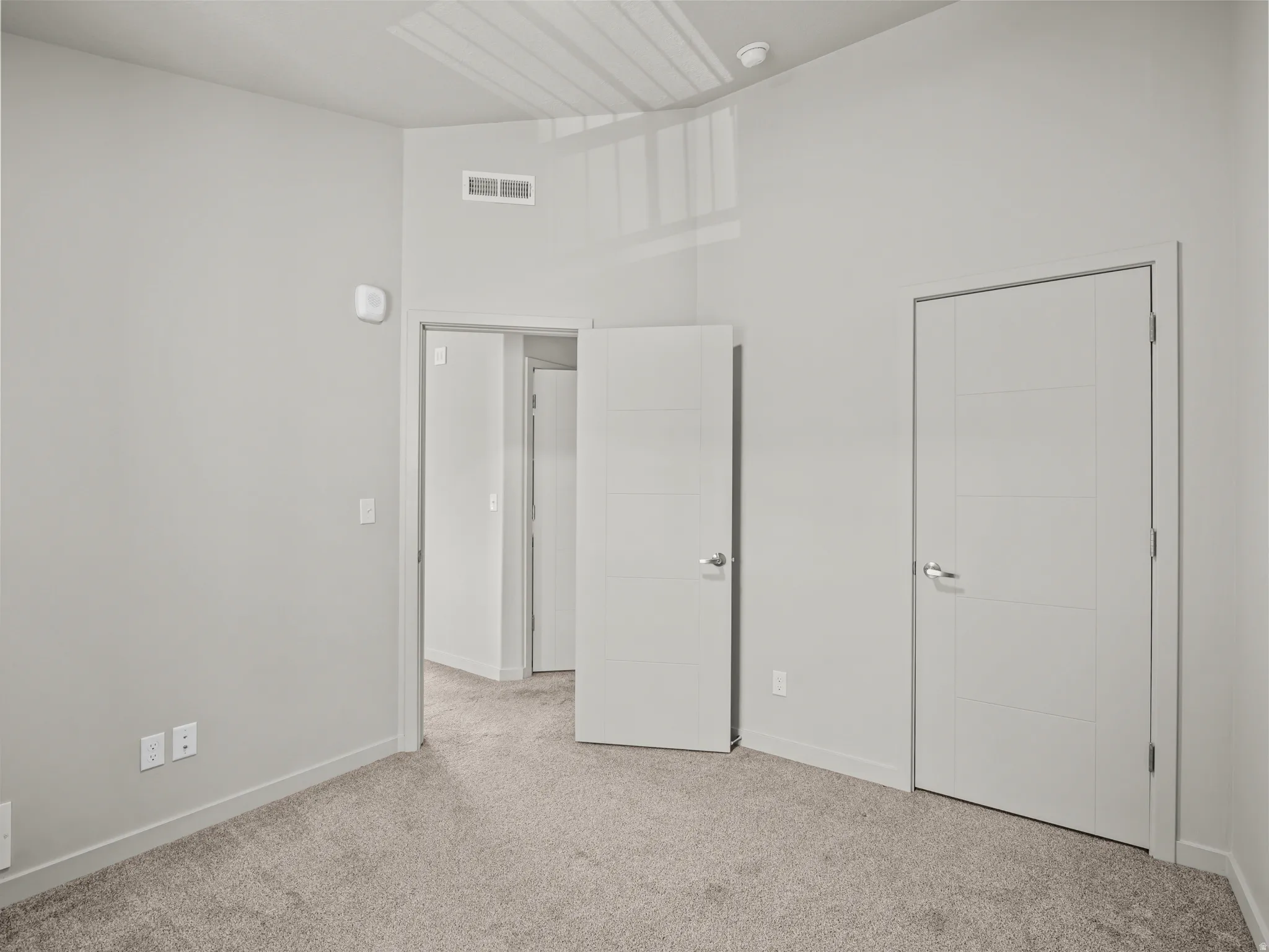 Unfurnished bedroom with light carpet and baseboards