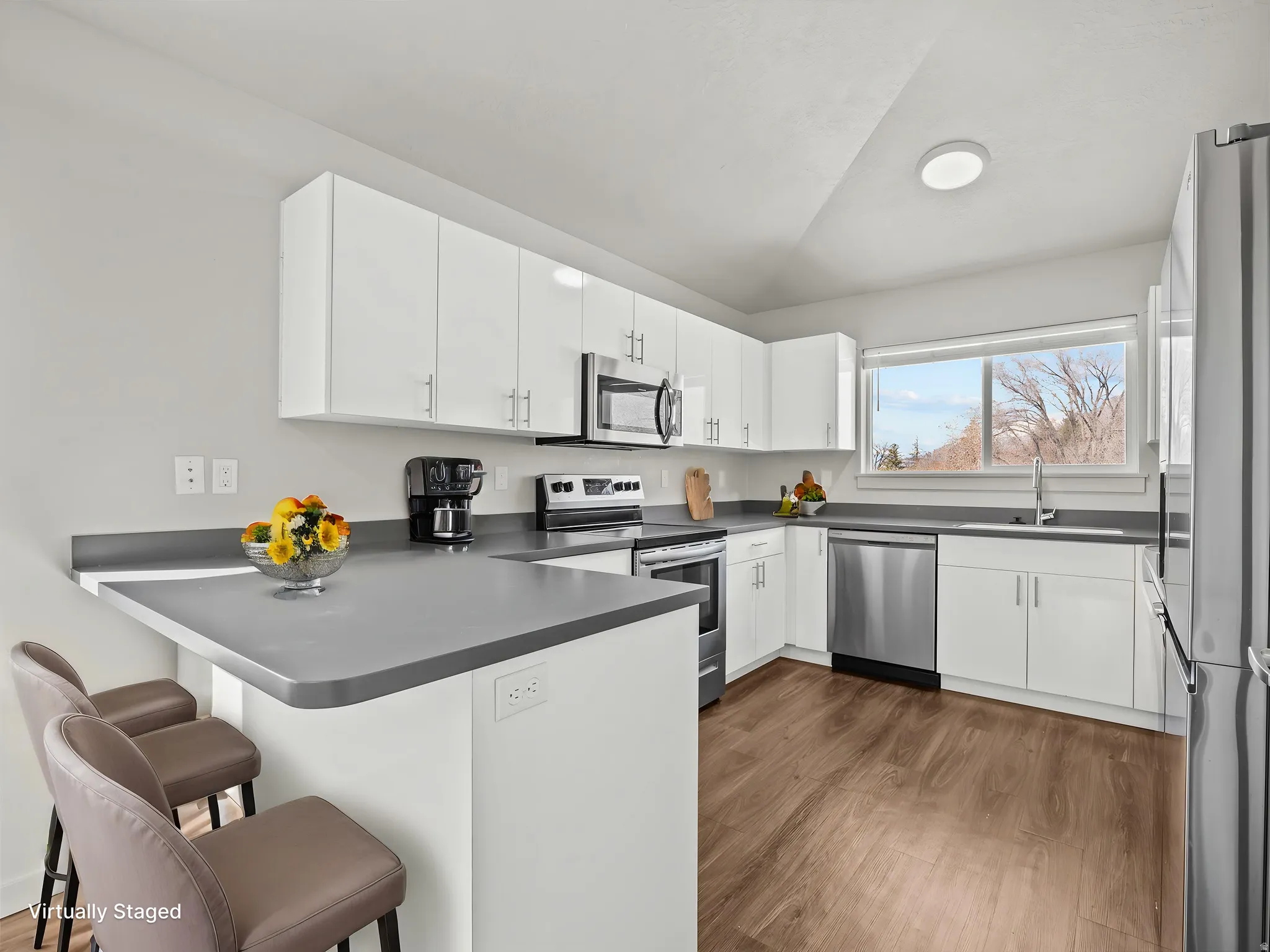 Modern kitchen with white cabinetry, stainless steel appliances, and wood-finish flooring