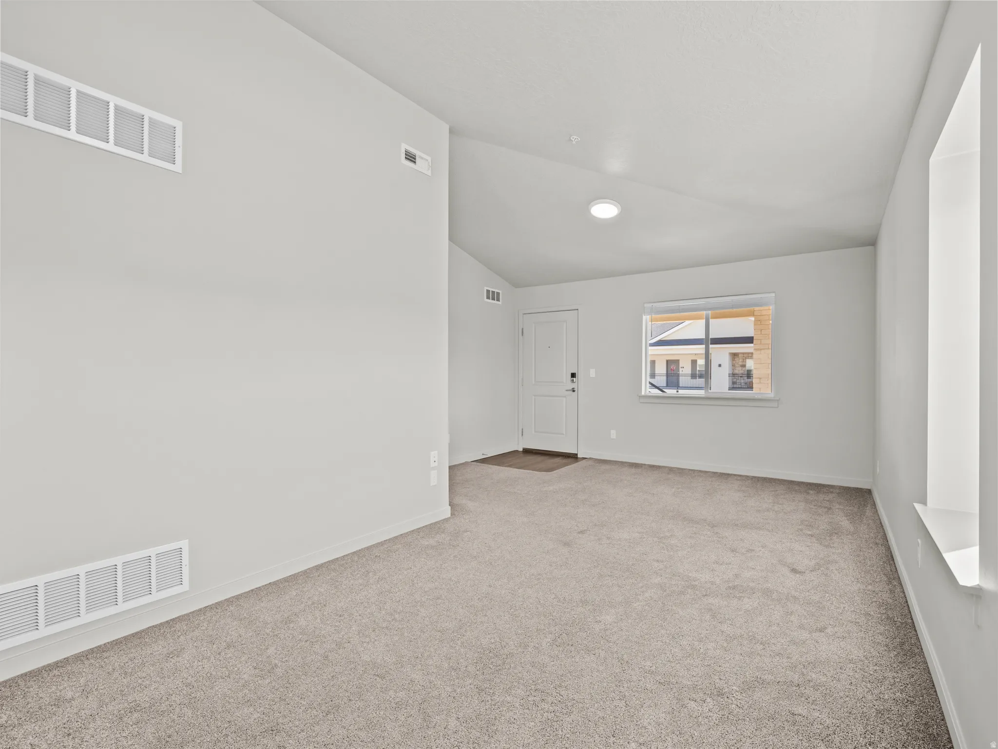 Spare room with vaulted ceiling and light carpet