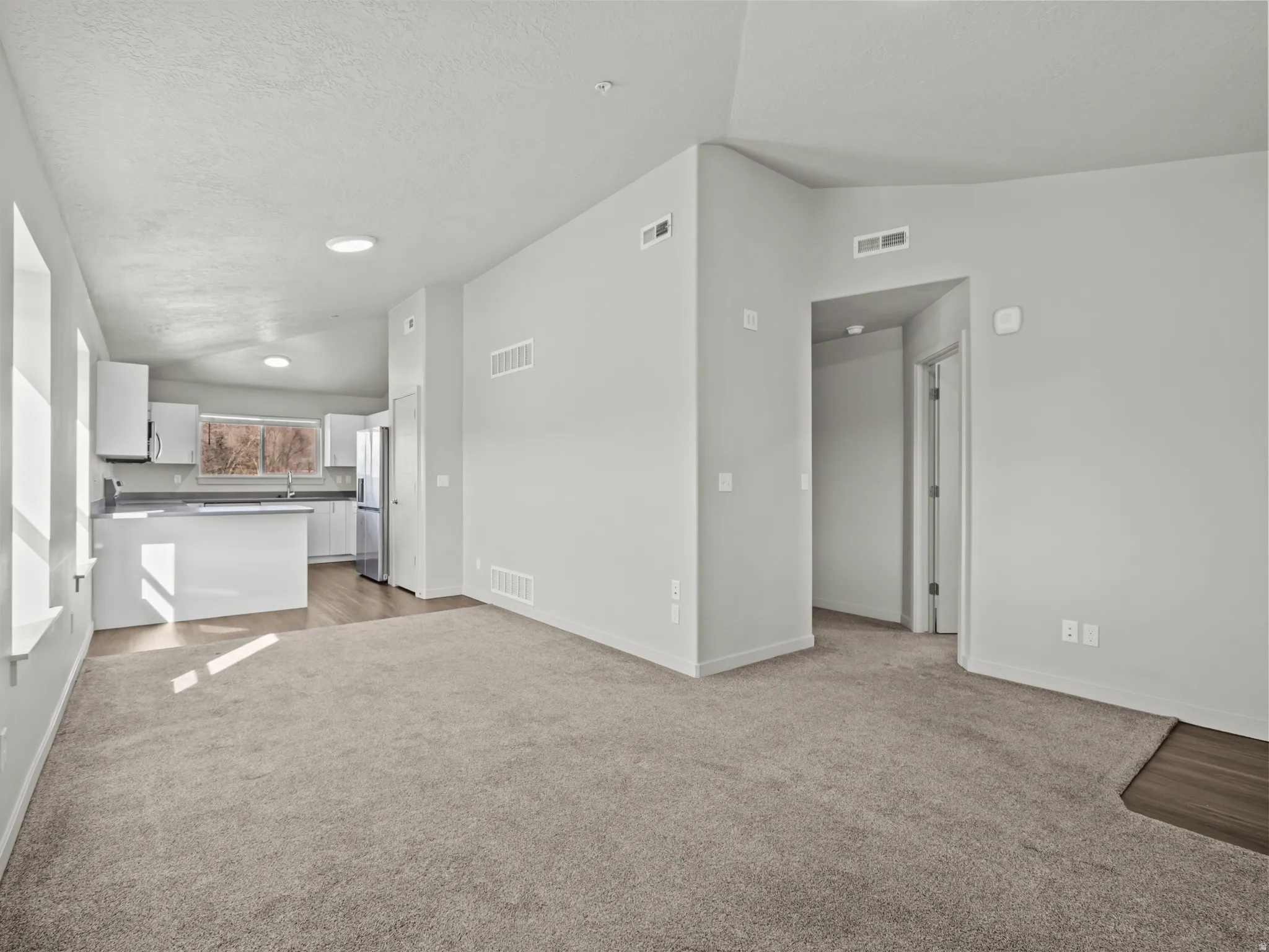 Unfurnished living room featuring light colored carpet and baseboards