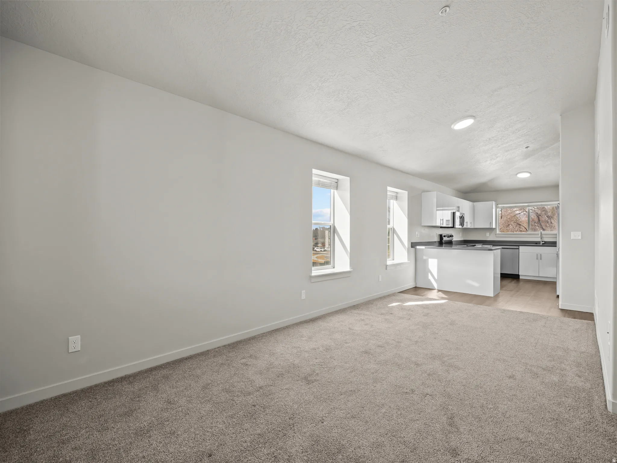 Unfurnished living room with light colored carpet and recessed lighting