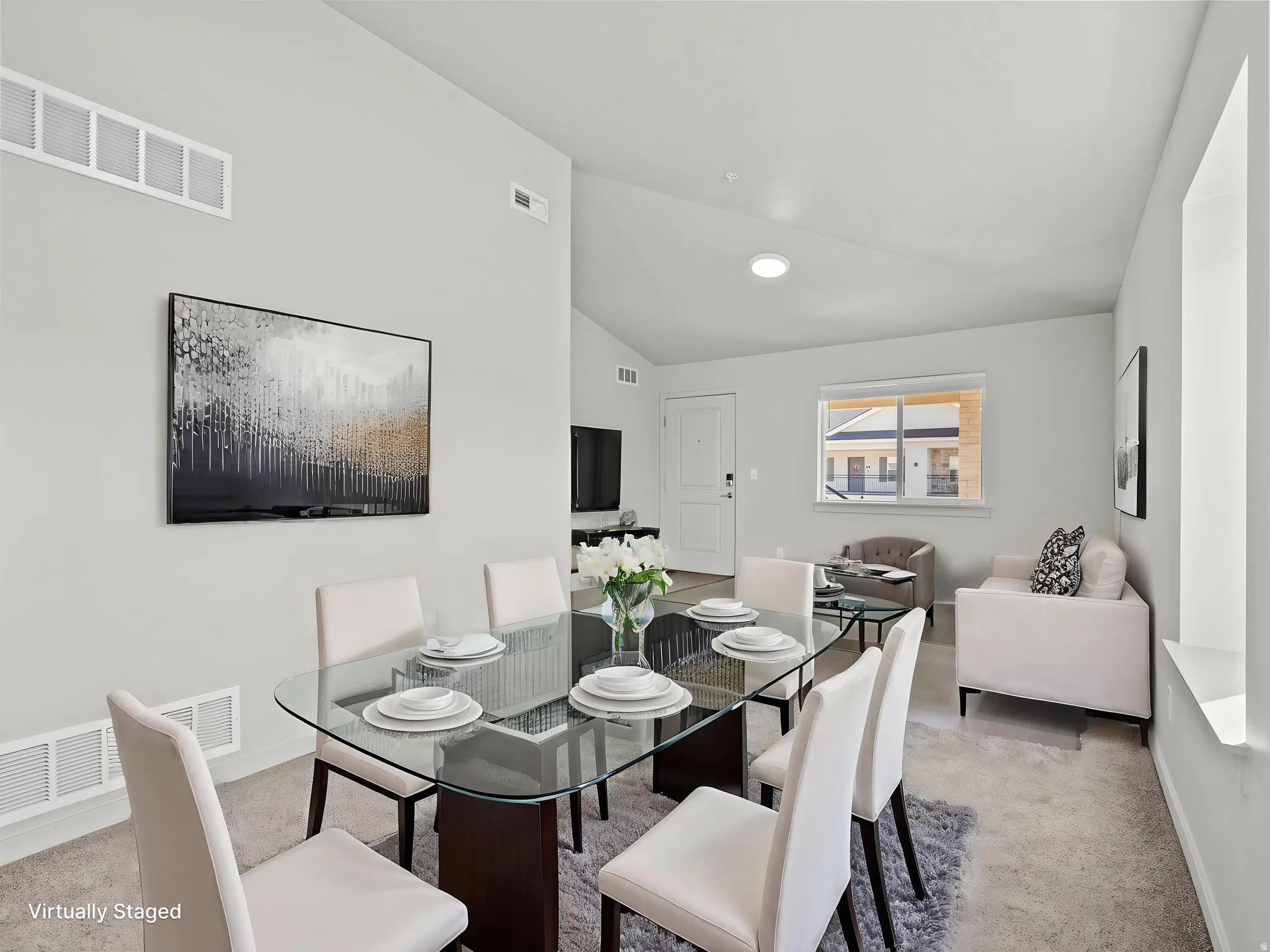 Open-concept dining and living area featuring high vaulted ceilings, light-toned walls, and carpeted flooring