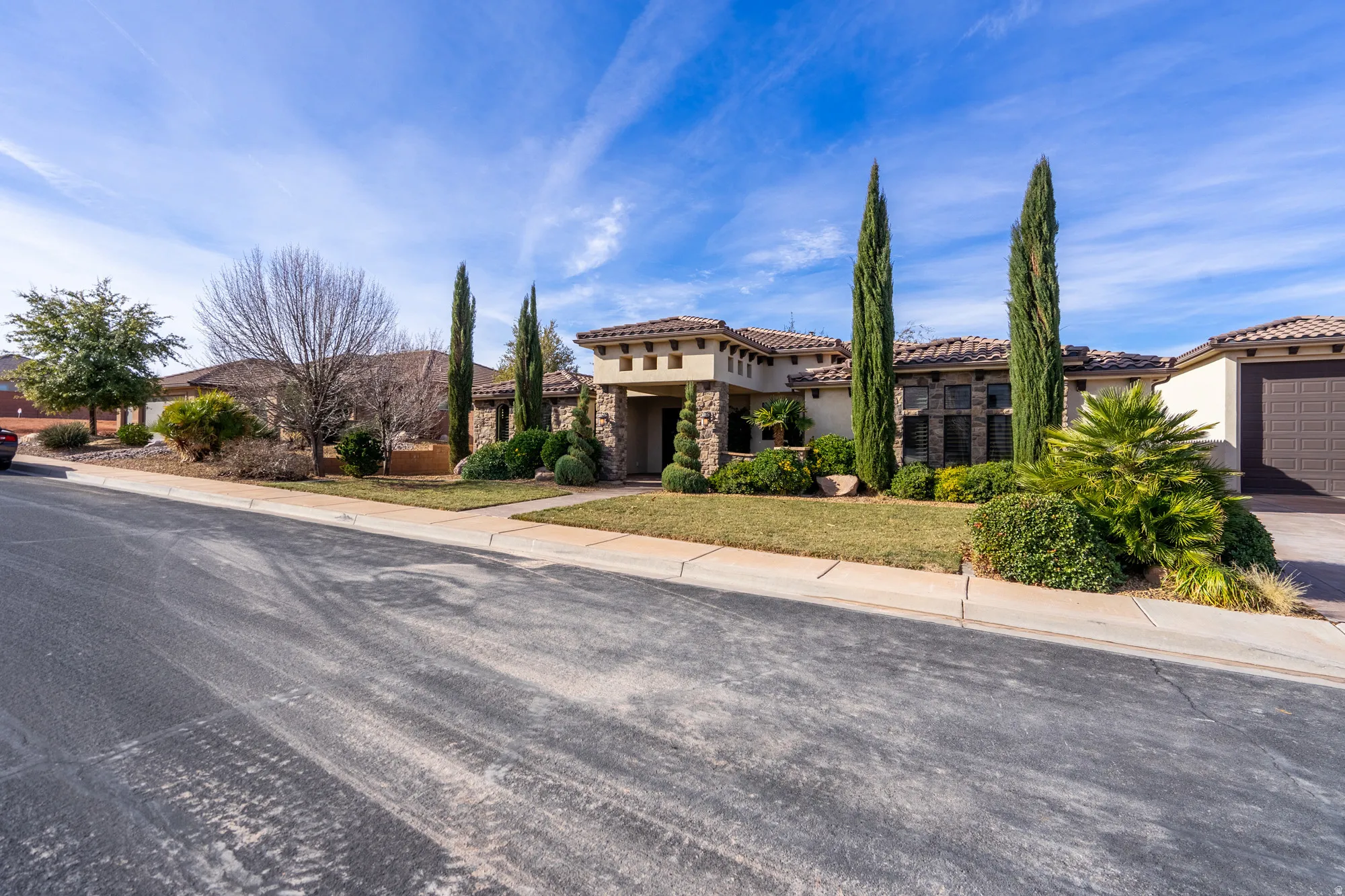Mediterranean / spanish home with stone siding, a front yard, a tile roof, and stucco siding