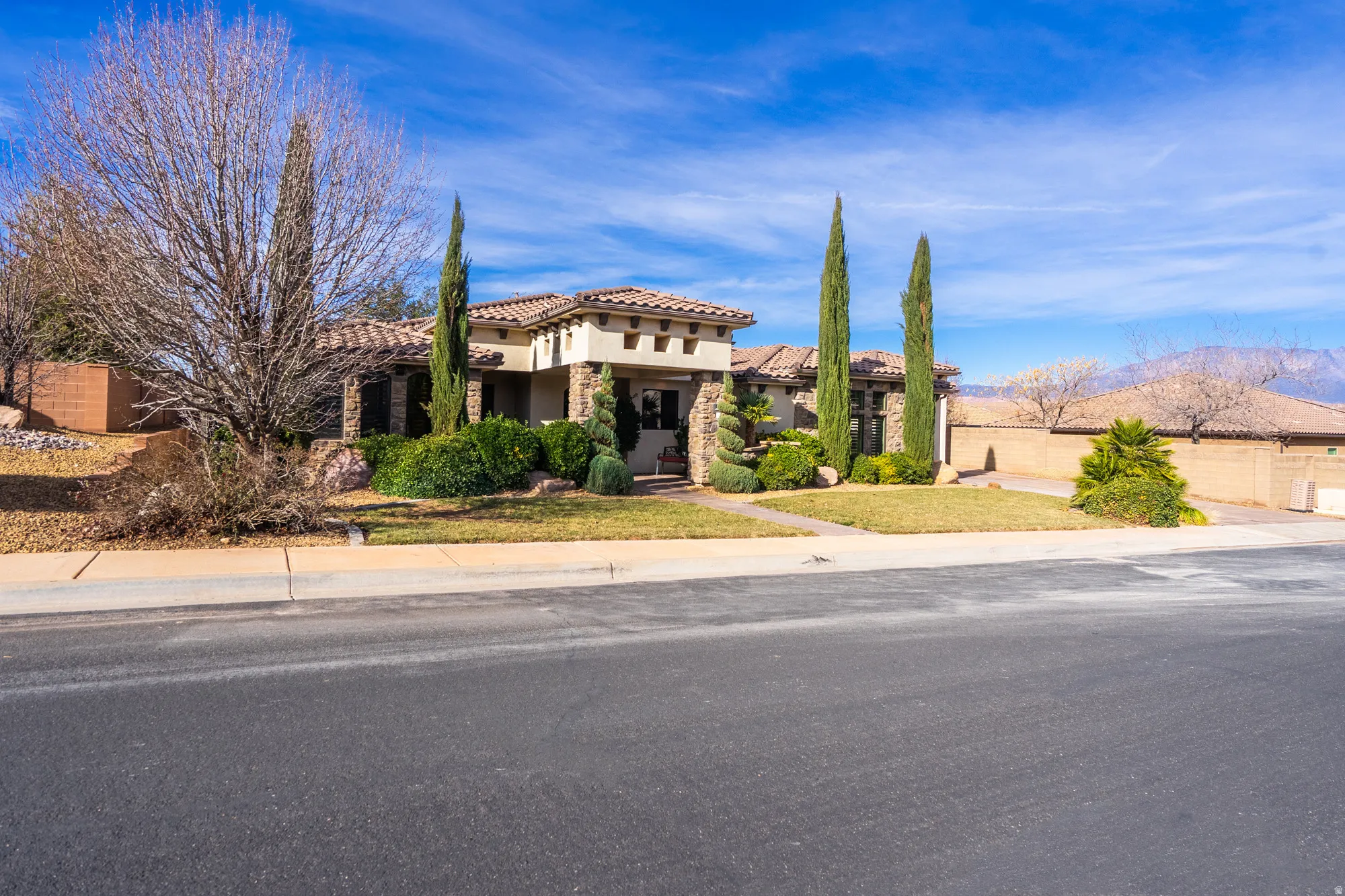 View of front of property with stone siding, a tile roof, and stucco siding