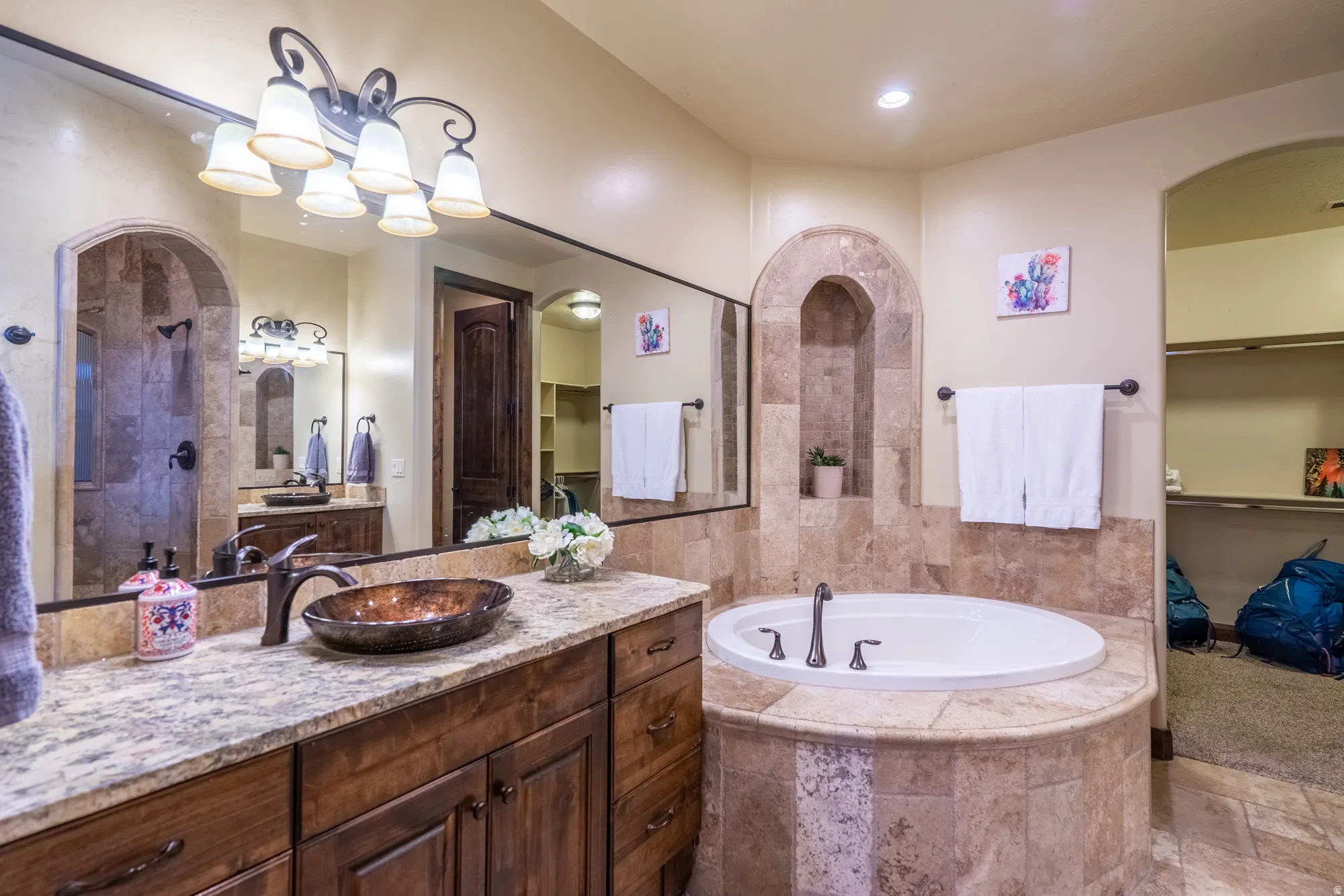 Full bath featuring a walk in closet, vanity, a garden tub, tiled shower, and stone finish floors