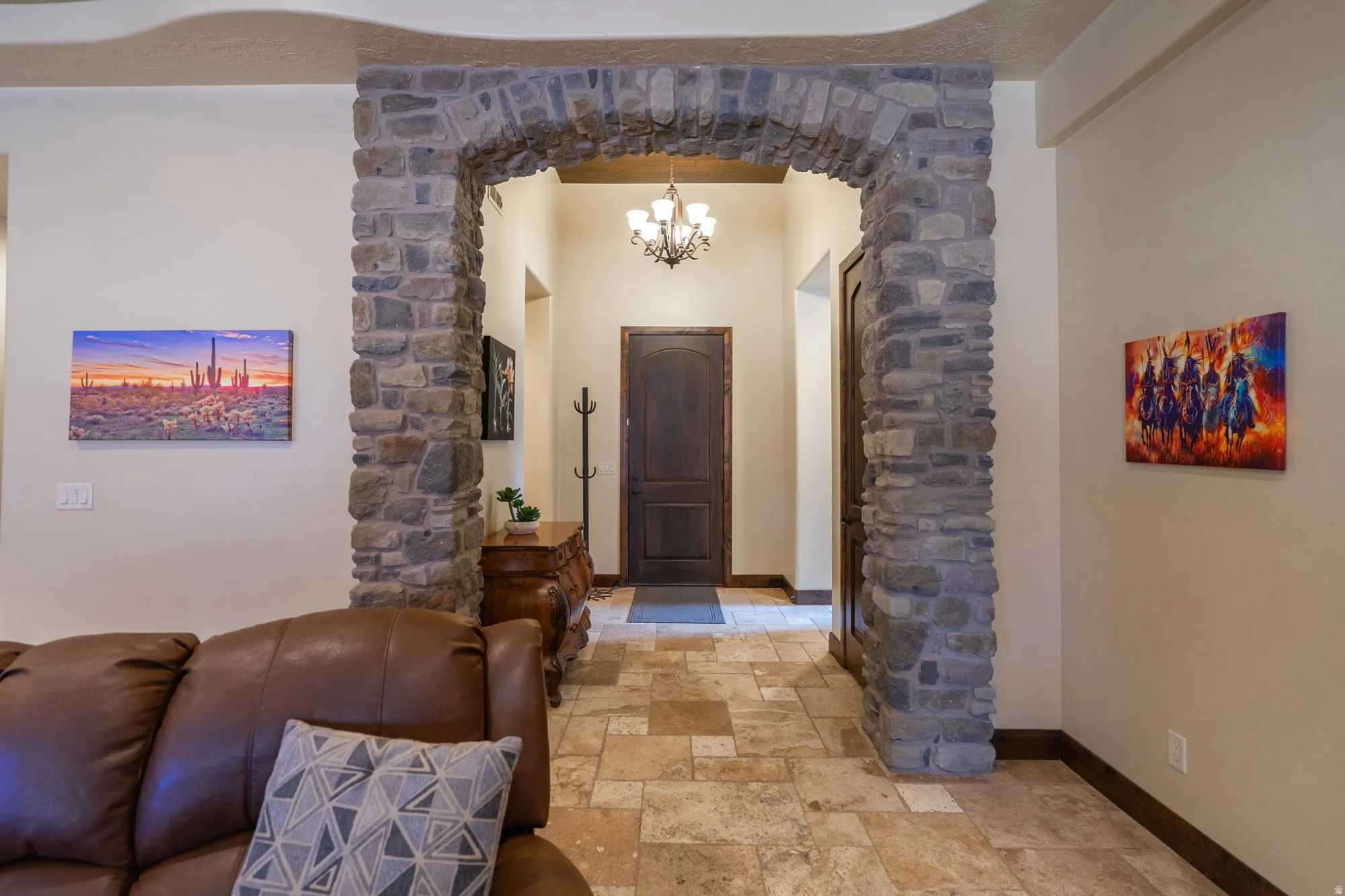 Foyer entrance with suspended lighting, stone tile floors, and arched walkways
