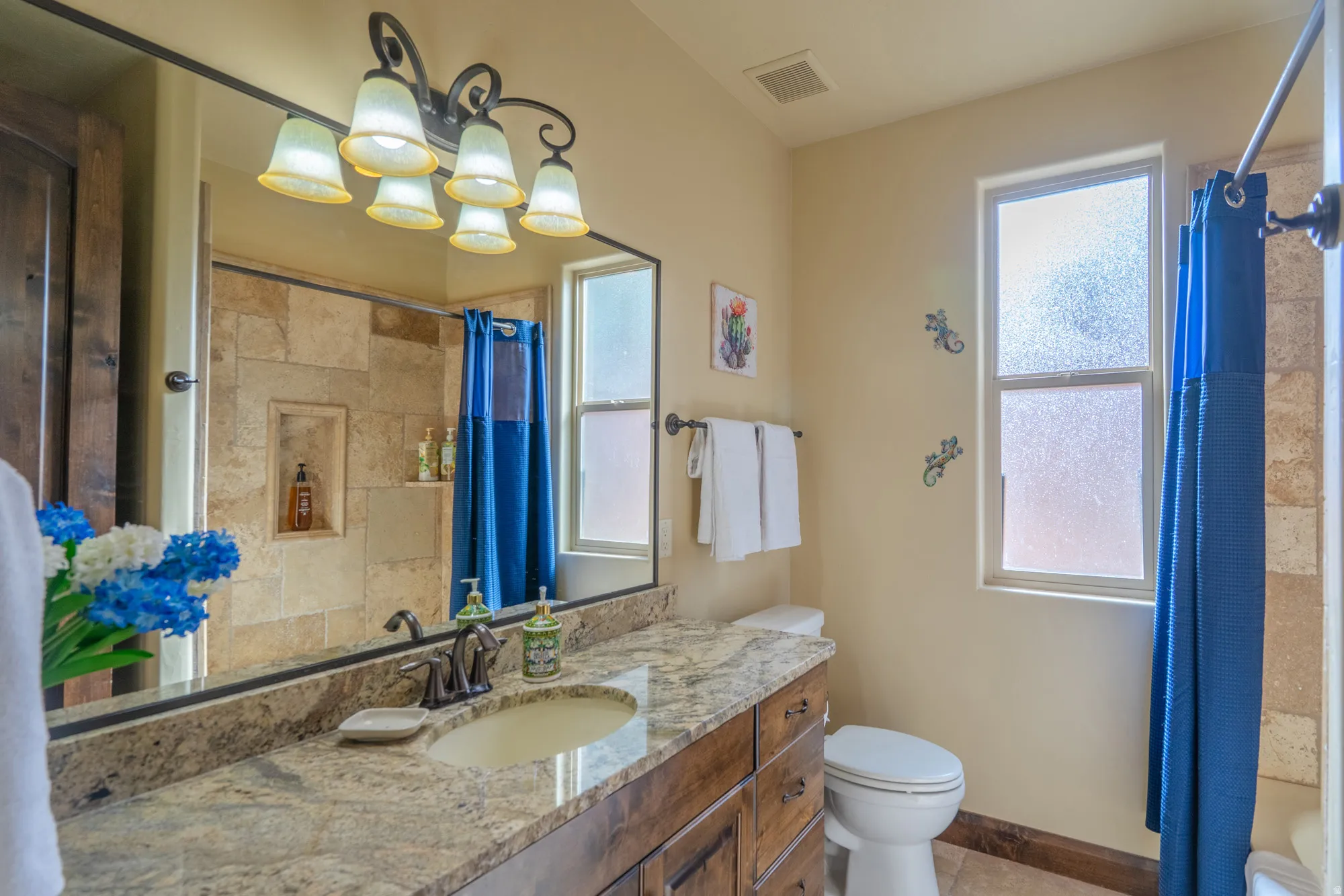 Bathroom featuring vanity, a shower with curtain, suspended lighting, and light tile patterned flooring