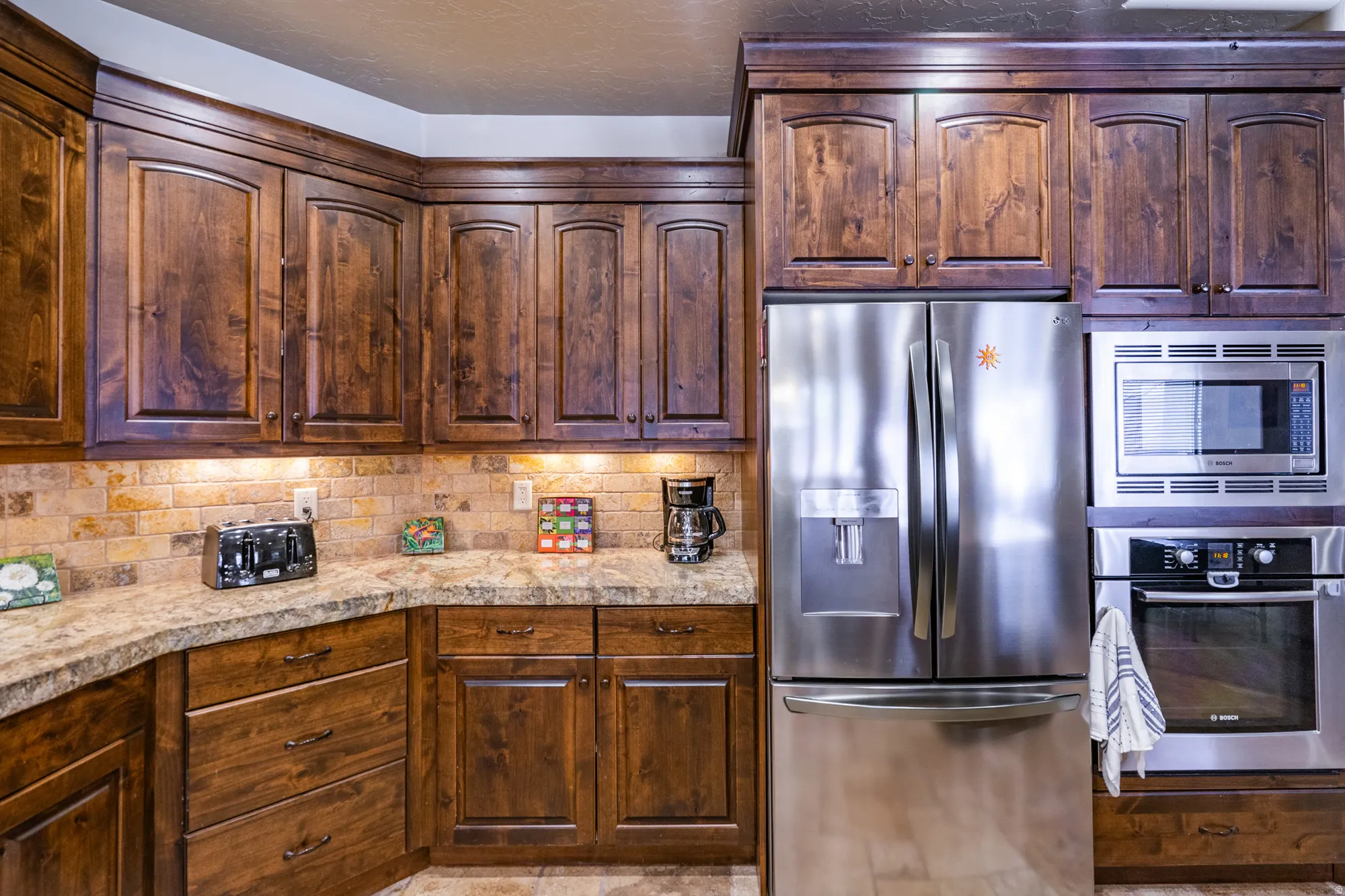 Kitchen with stainless steel appliances, decorative backsplash, and dark wood finish cabinets