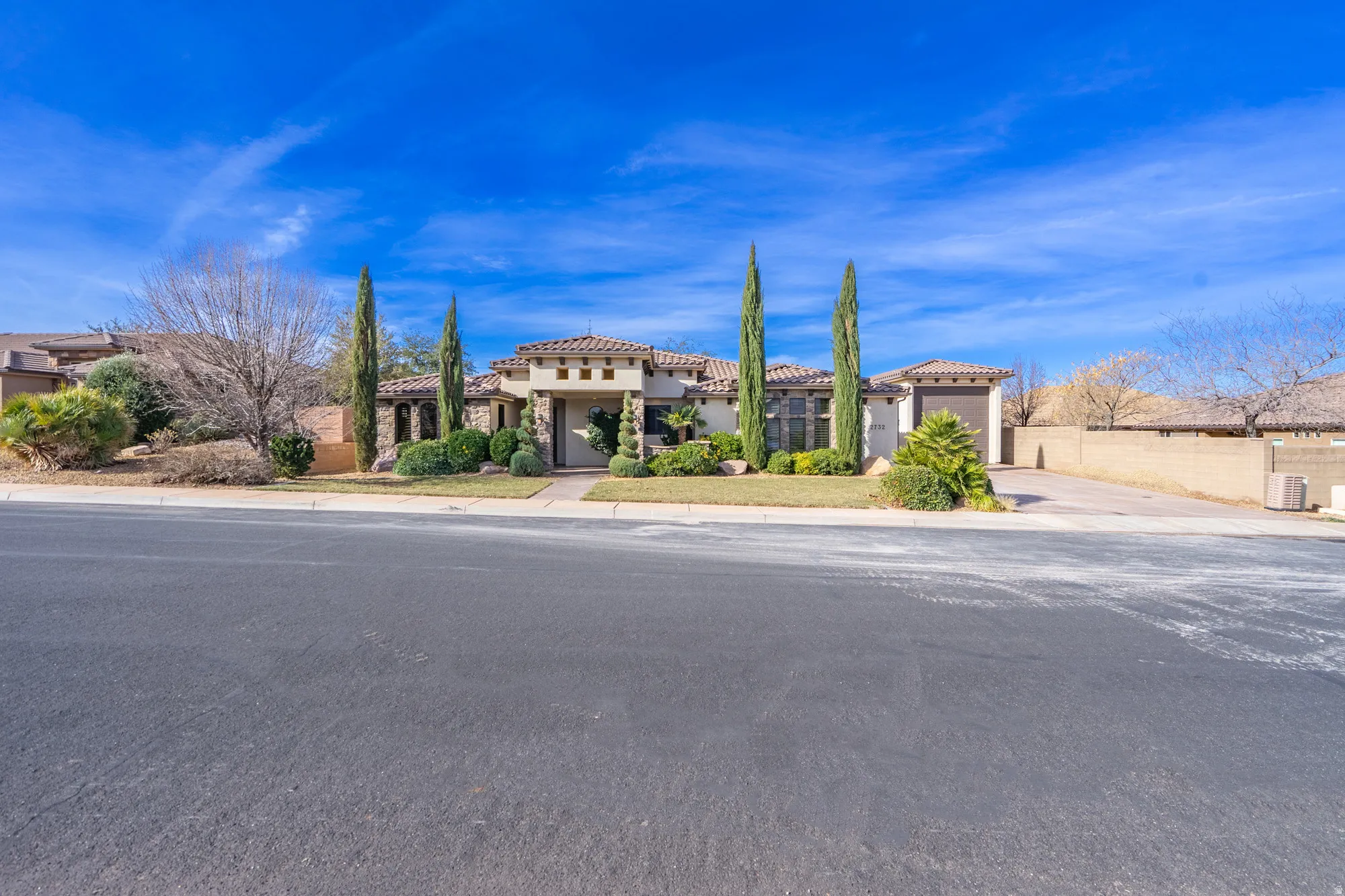 Mediterranean / spanish-style home with driveway, an attached garage, a tiled roof, stone siding, and stucco siding