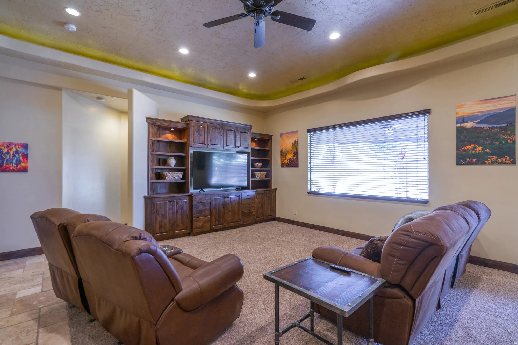 Living room featuring a tray ceiling, ceiling fan, recessed lighting, and light stone finish floors