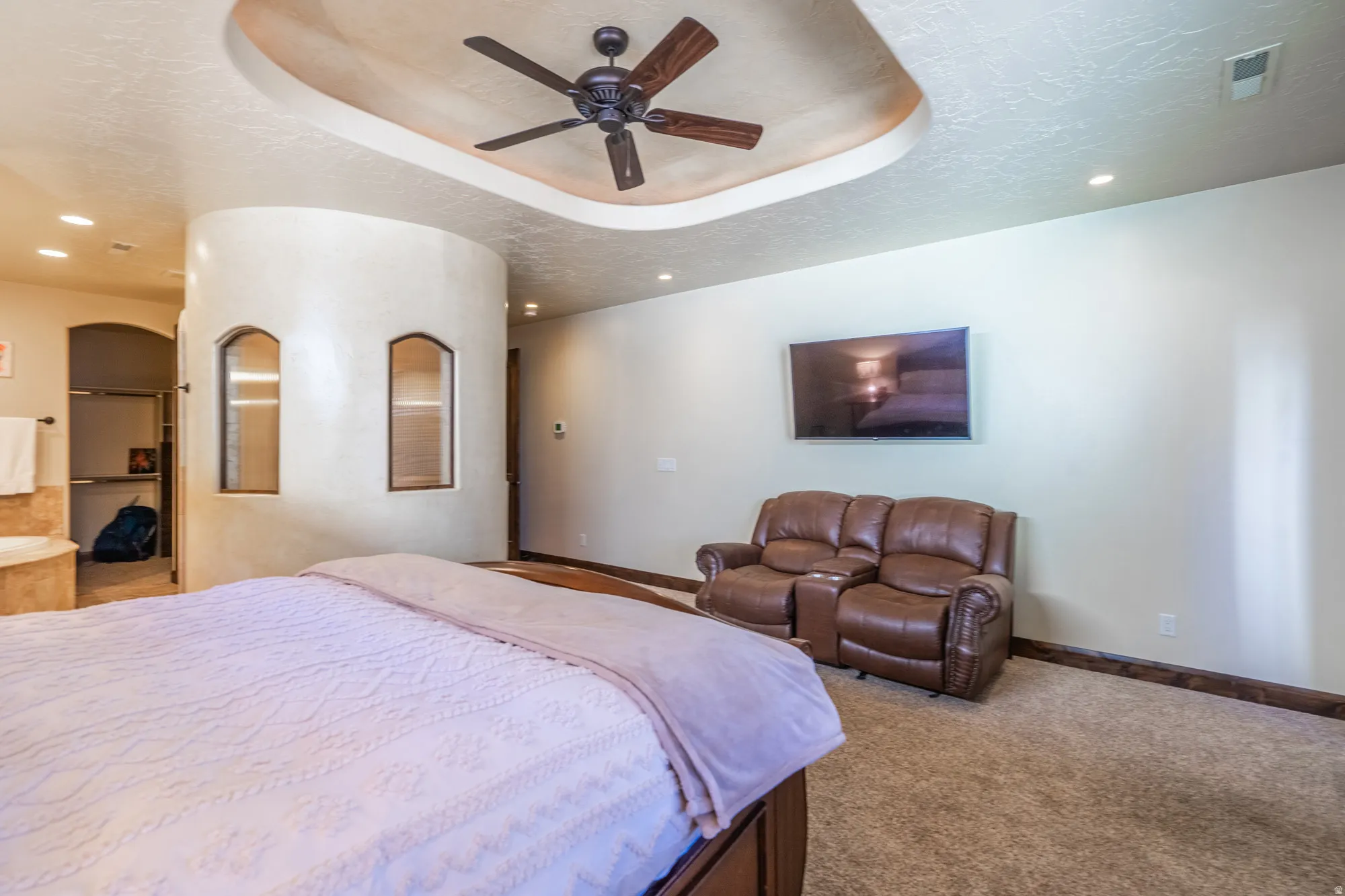Bedroom with recessed lighting, light carpet, ceiling fan, a textured ceiling, and a tray ceiling