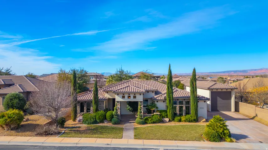 View of front of property with concrete driveway, stone siding, a residential view, stucco siding, and a front yard