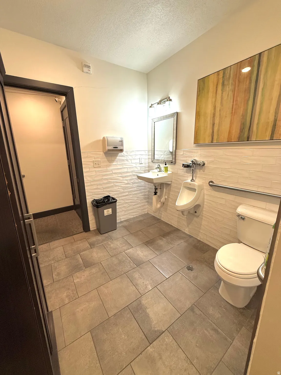 Bathroom featuring a textured ceiling, tile walls, and a wainscoted wall