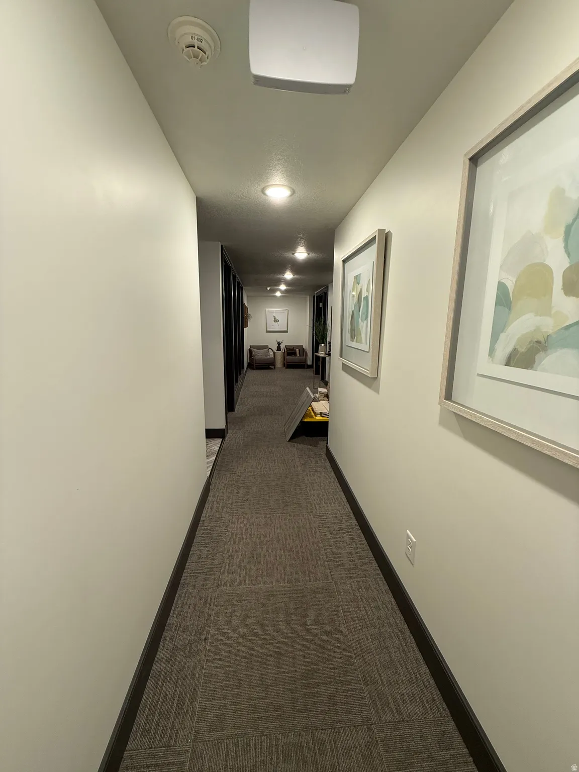 Hall featuring dark carpet and baseboards