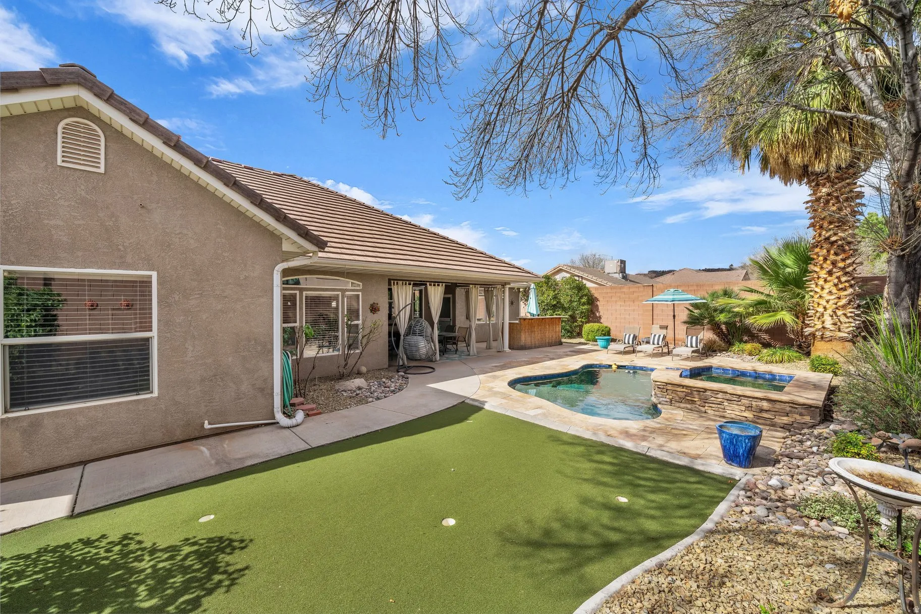 Integrated pool / spa featuring a sunroom, a putting green, and a patio