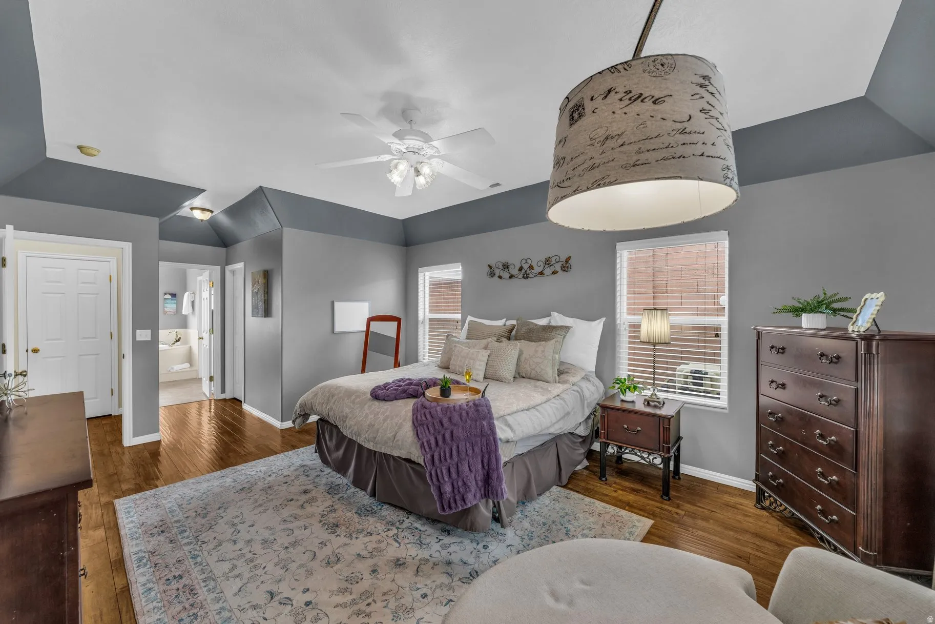 Bedroom with dark wood finished floors, ensuite bath, and ceiling fan
