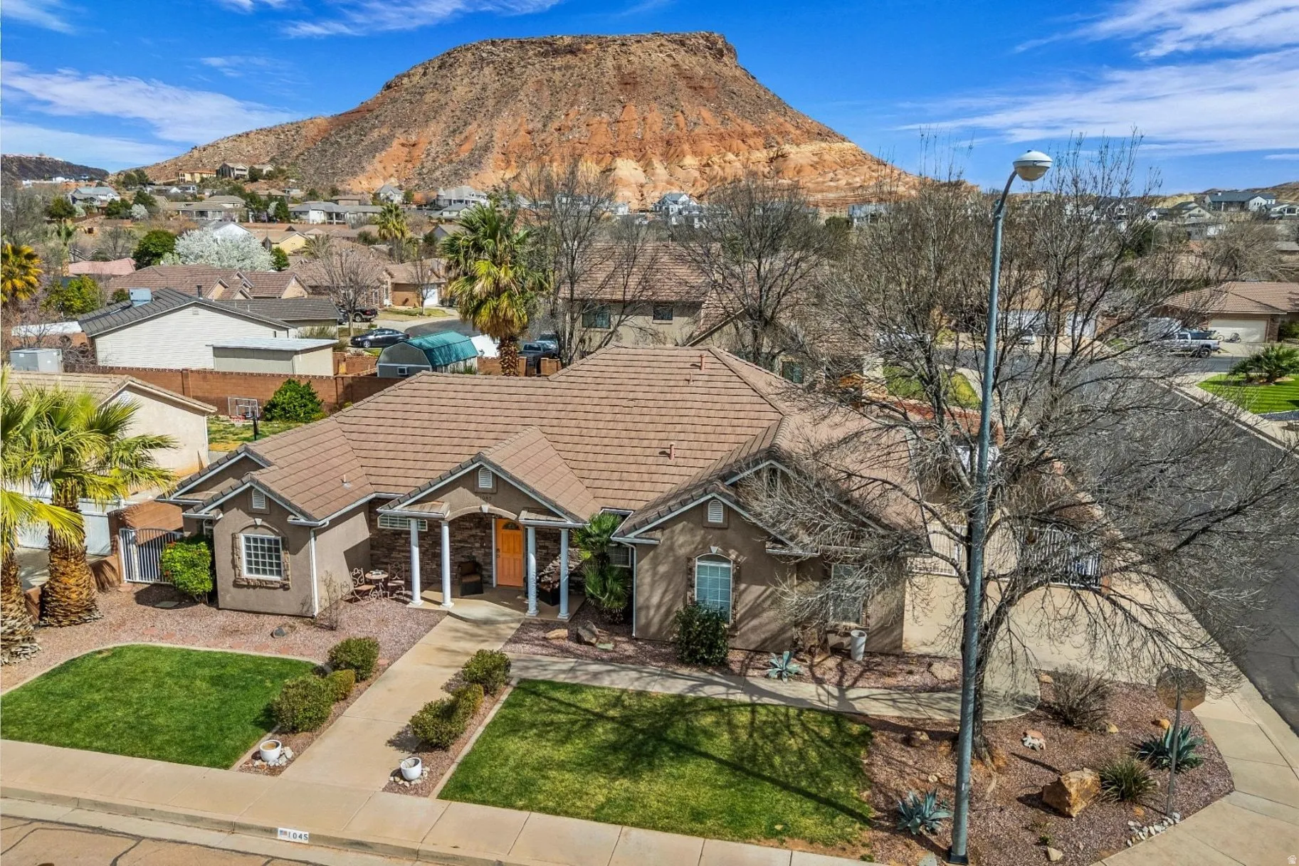 View of front facade with a mountain view, a residential view, a front yard, stone siding, and stucco siding