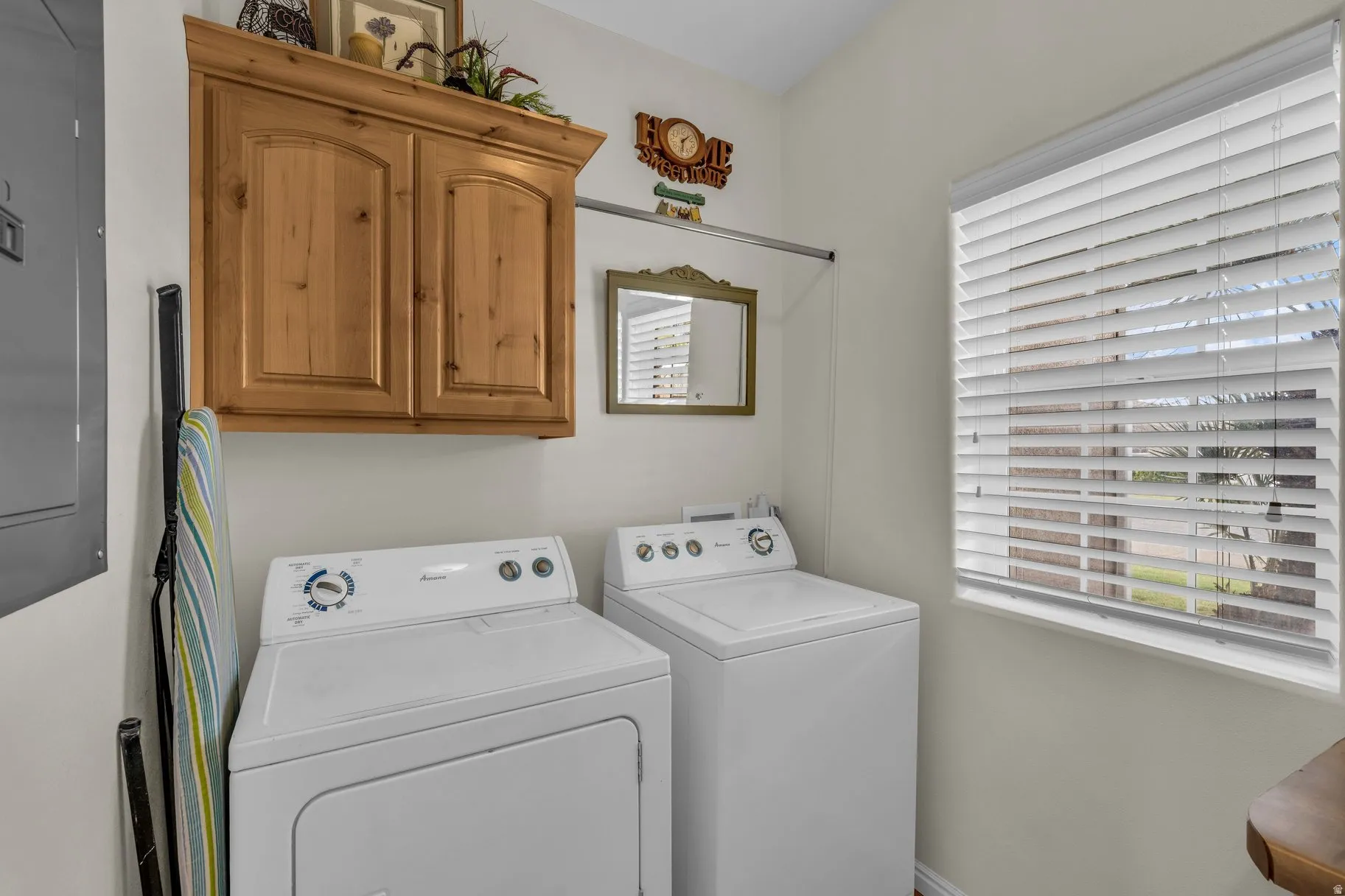 Laundry room featuring electric panel, plenty of natural light, washer and clothes dryer, and cabinet space