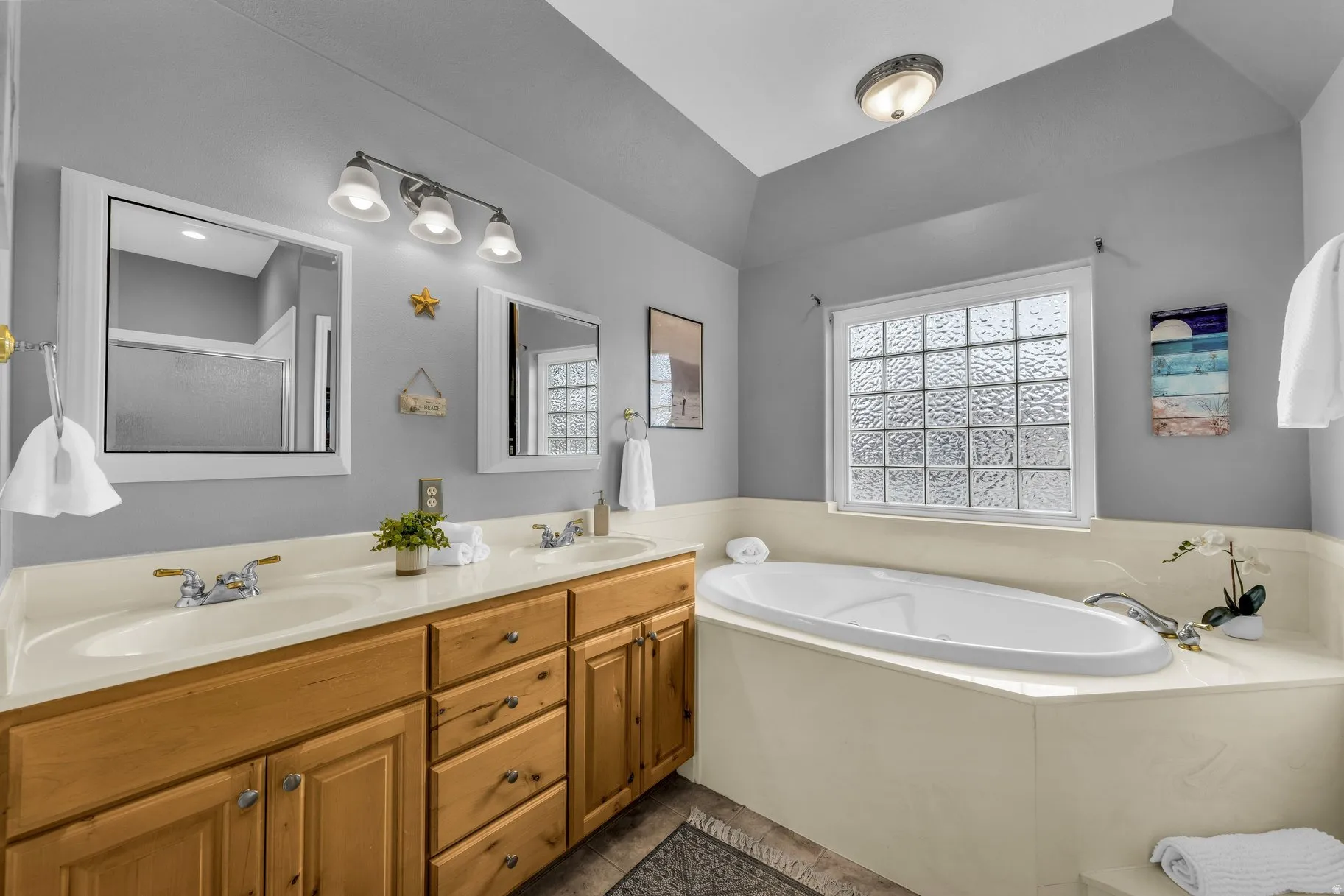 Bathroom featuring double vanity, a bath, and lofted ceiling