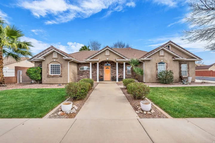 View of front facade featuring stucco siding, a tiled roof, stone siding, and covered porch