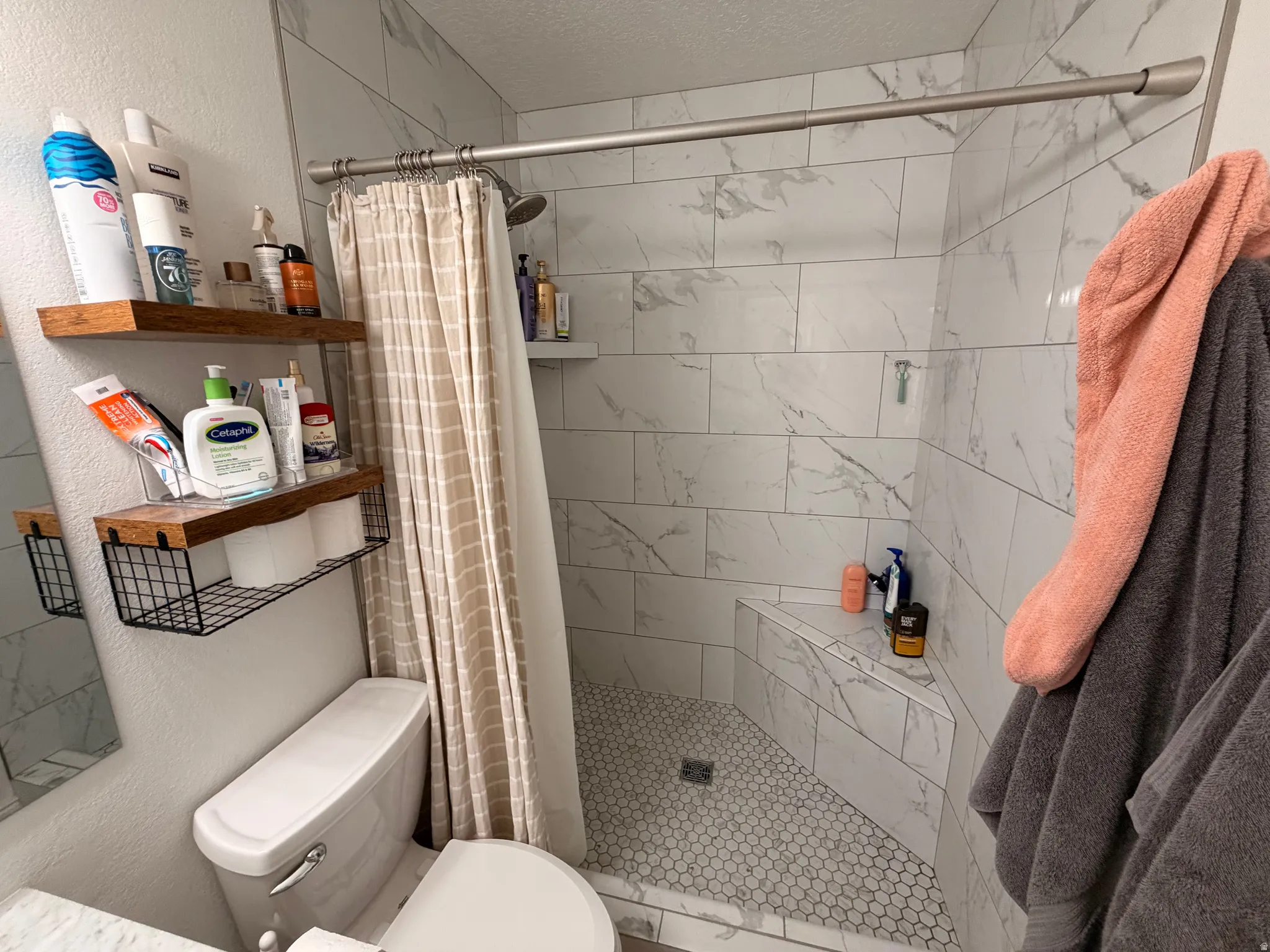 Full bathroom with a textured wall, a shower stall, and a textured ceiling
