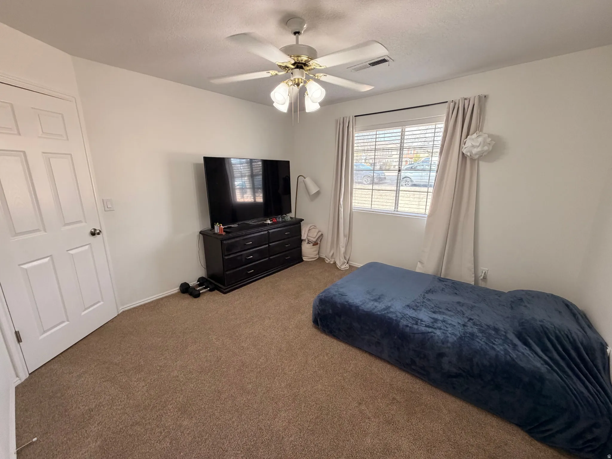Bedroom featuring ceiling fan, carpet flooring, and a textured ceiling