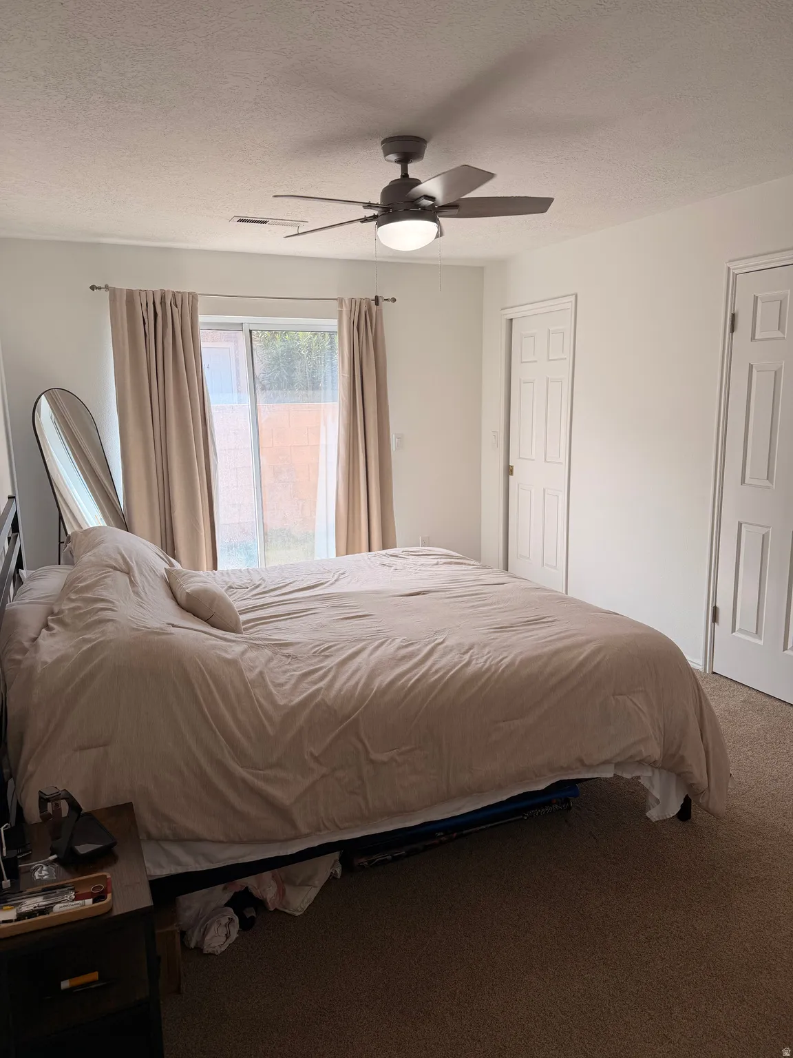 Carpeted bedroom featuring a textured ceiling and ceiling fan