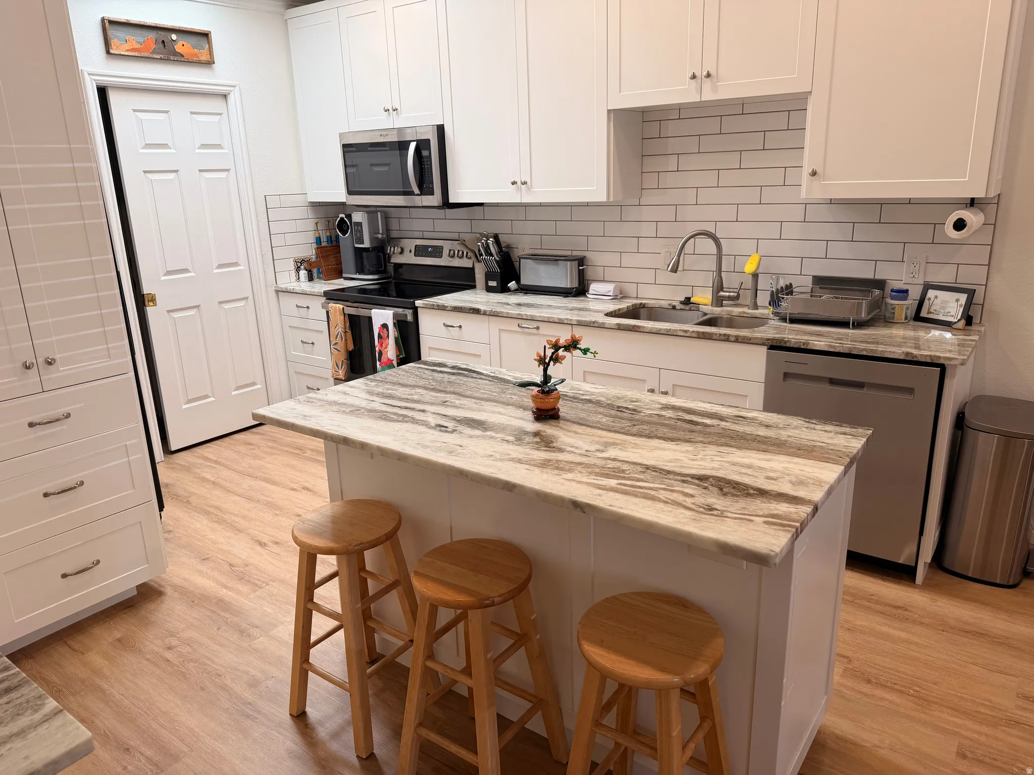 Kitchen featuring a breakfast bar area, white cabinets, stainless steel appliances, and light stone counters