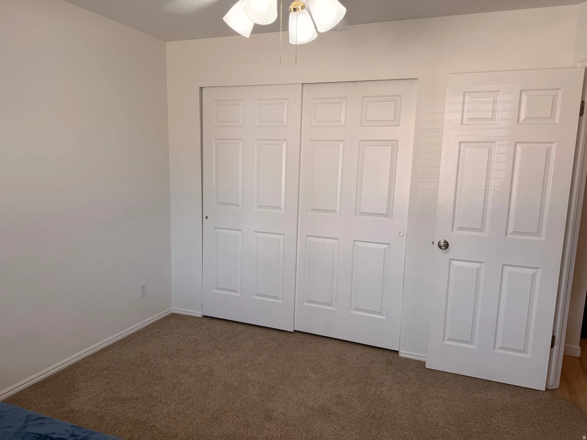 Unfurnished bedroom featuring dark carpet, a closet, and ceiling fan