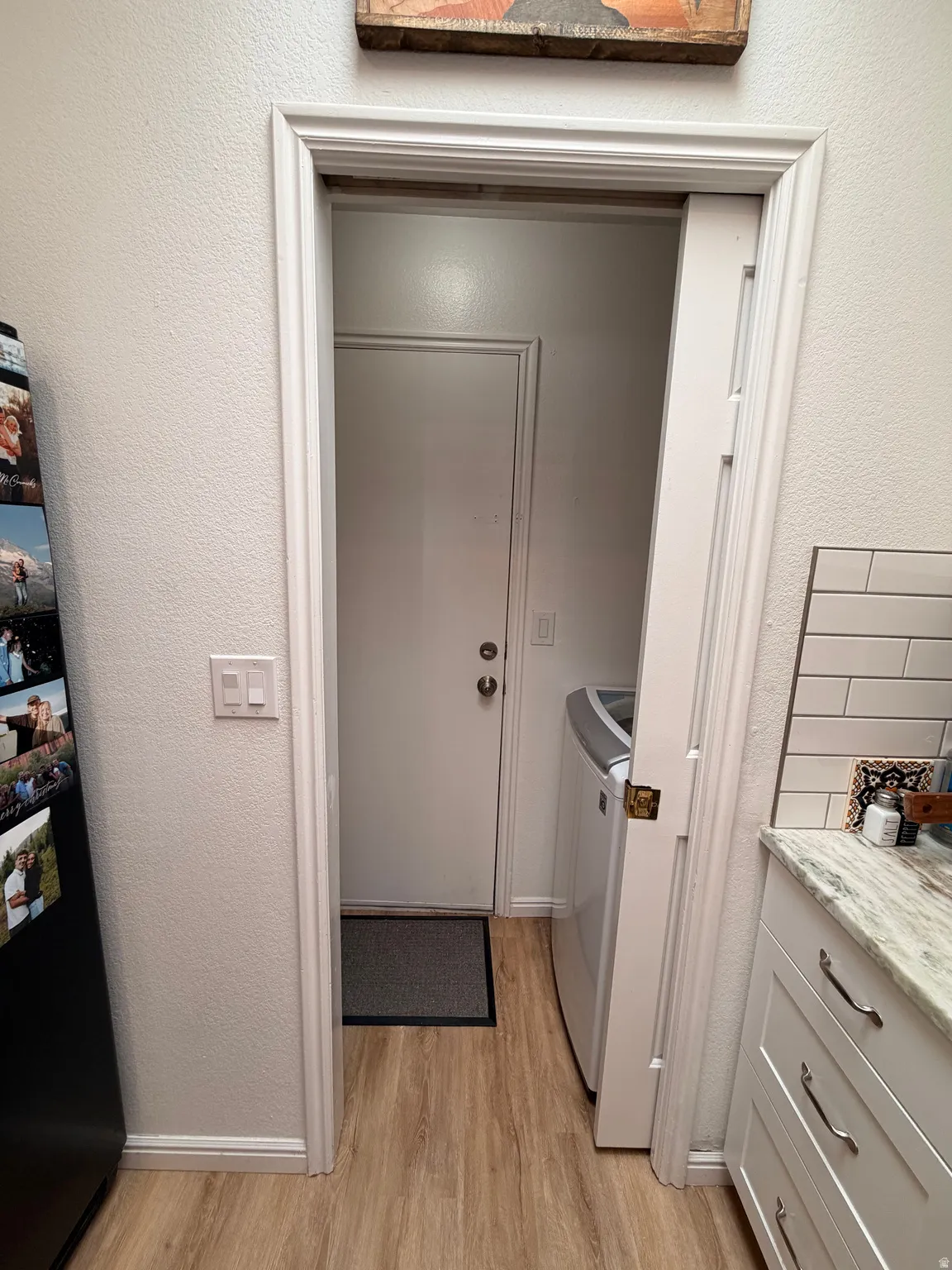 Laundry room with a textured wall, light wood-style flooring, and washing machine and dryer