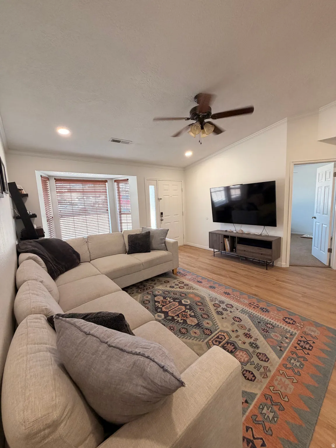 Living area with wood finished floors, a ceiling fan, and ornamental molding