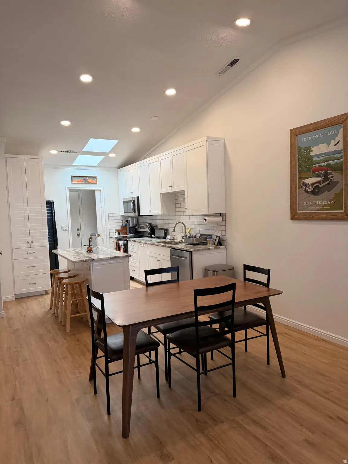 Dining space featuring light wood-style floors, vaulted ceiling, a skylight, and recessed lighting