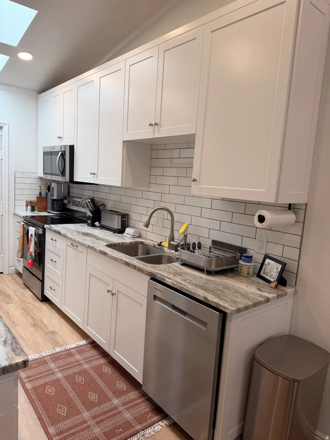 Kitchen featuring stainless steel appliances, light stone counters, white cabinetry, tasteful backsplash, and recessed lighting